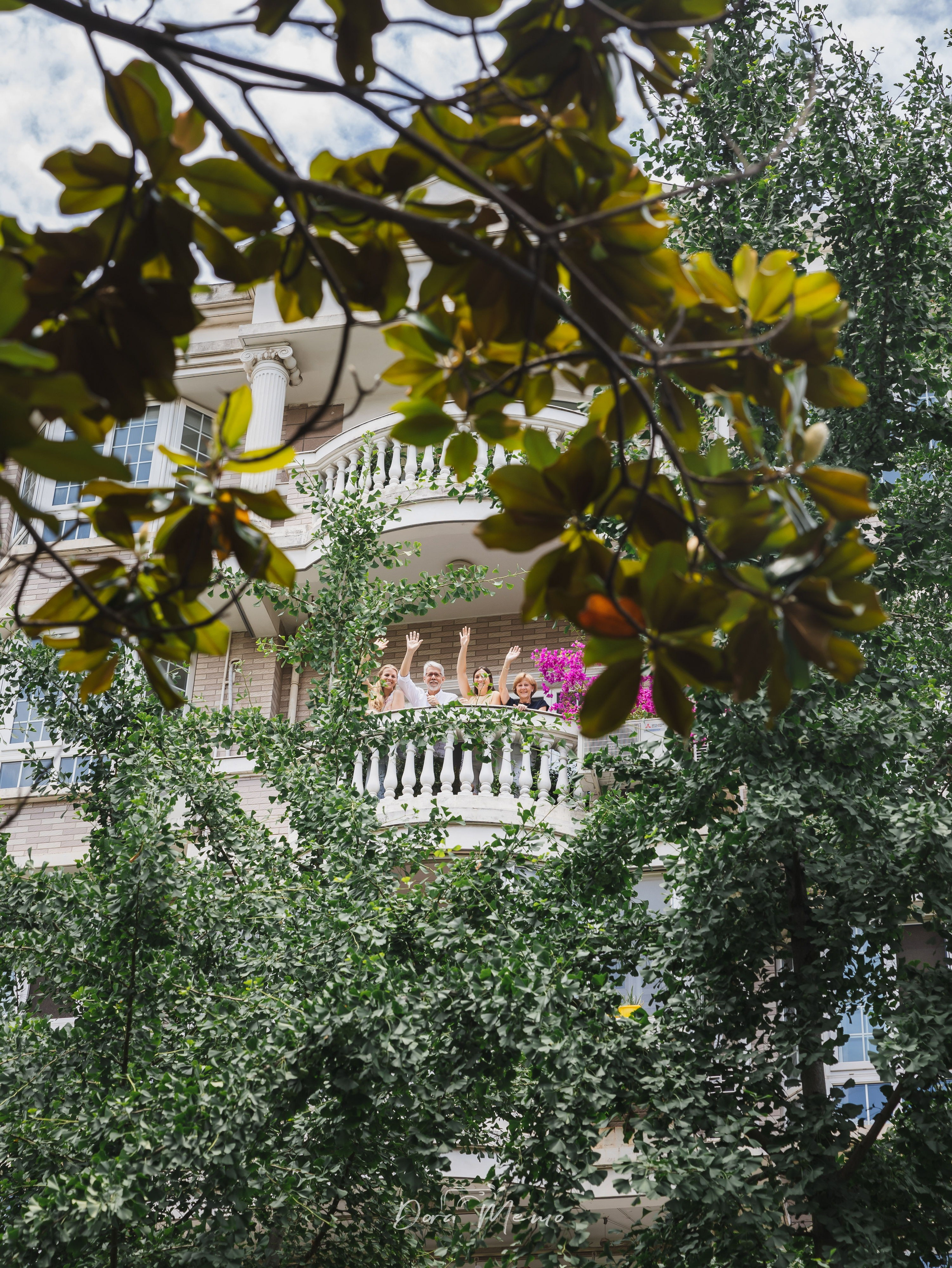 A family waving from the balcony of their Shanghai home during a farewell photo session.