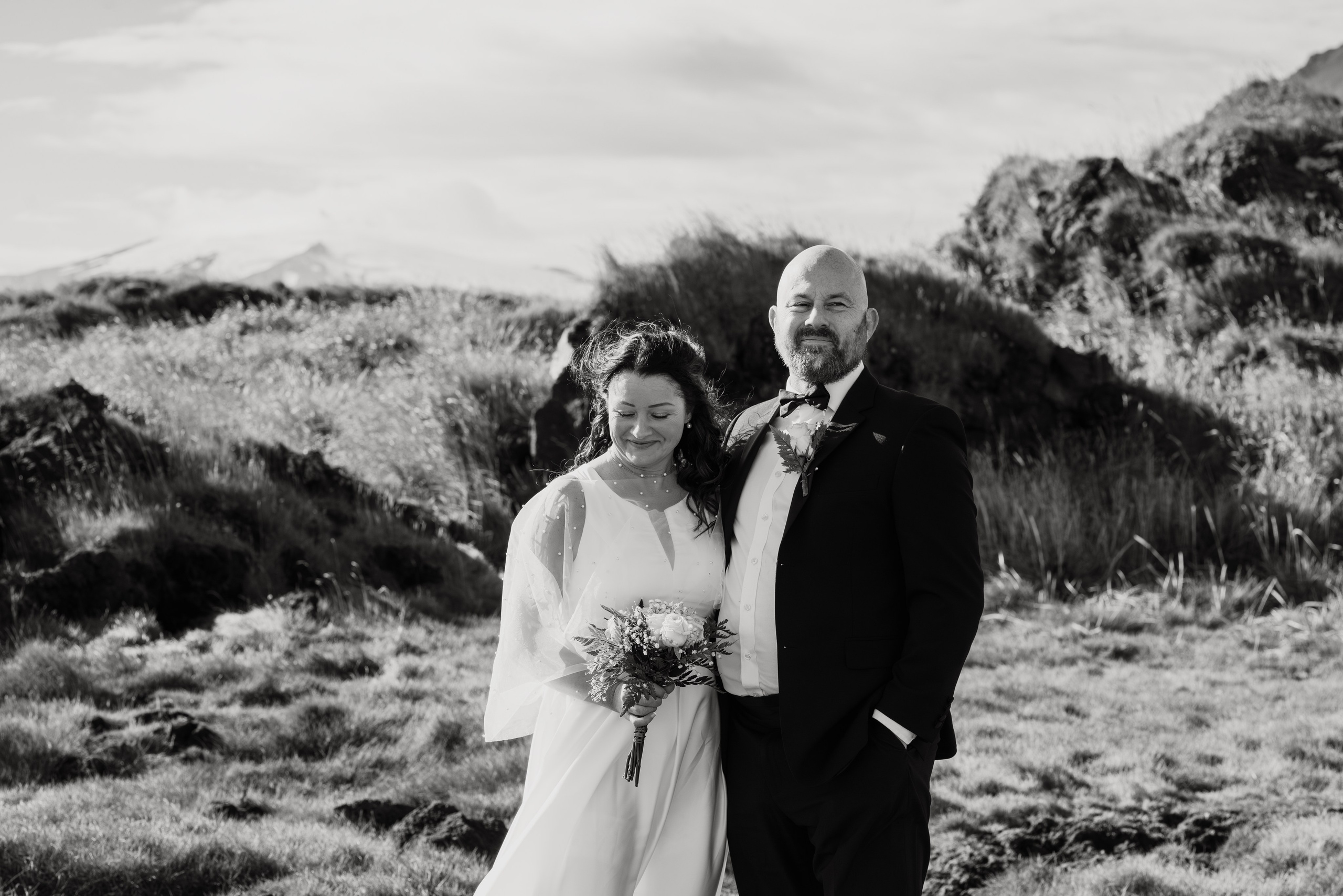 Bride in a flowing dress, gently petting a sheep near the rugged coastline of Snæfellsnes.