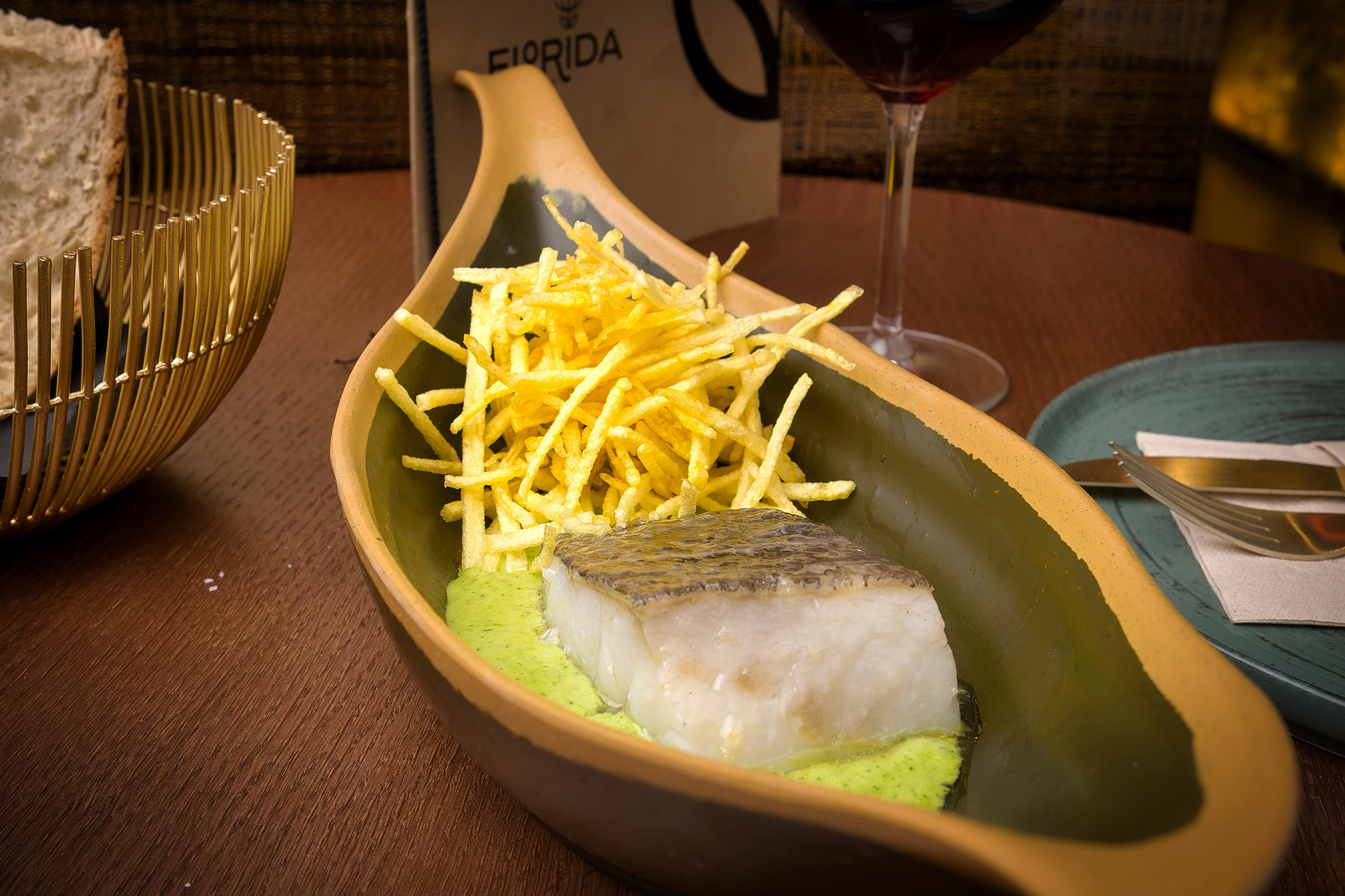 Imagen de comida cuidadosamente emplatada sobre fondo oscuro, capturando detalles y contraste visual.Plato de bacalado cuidadosamente emplatado.