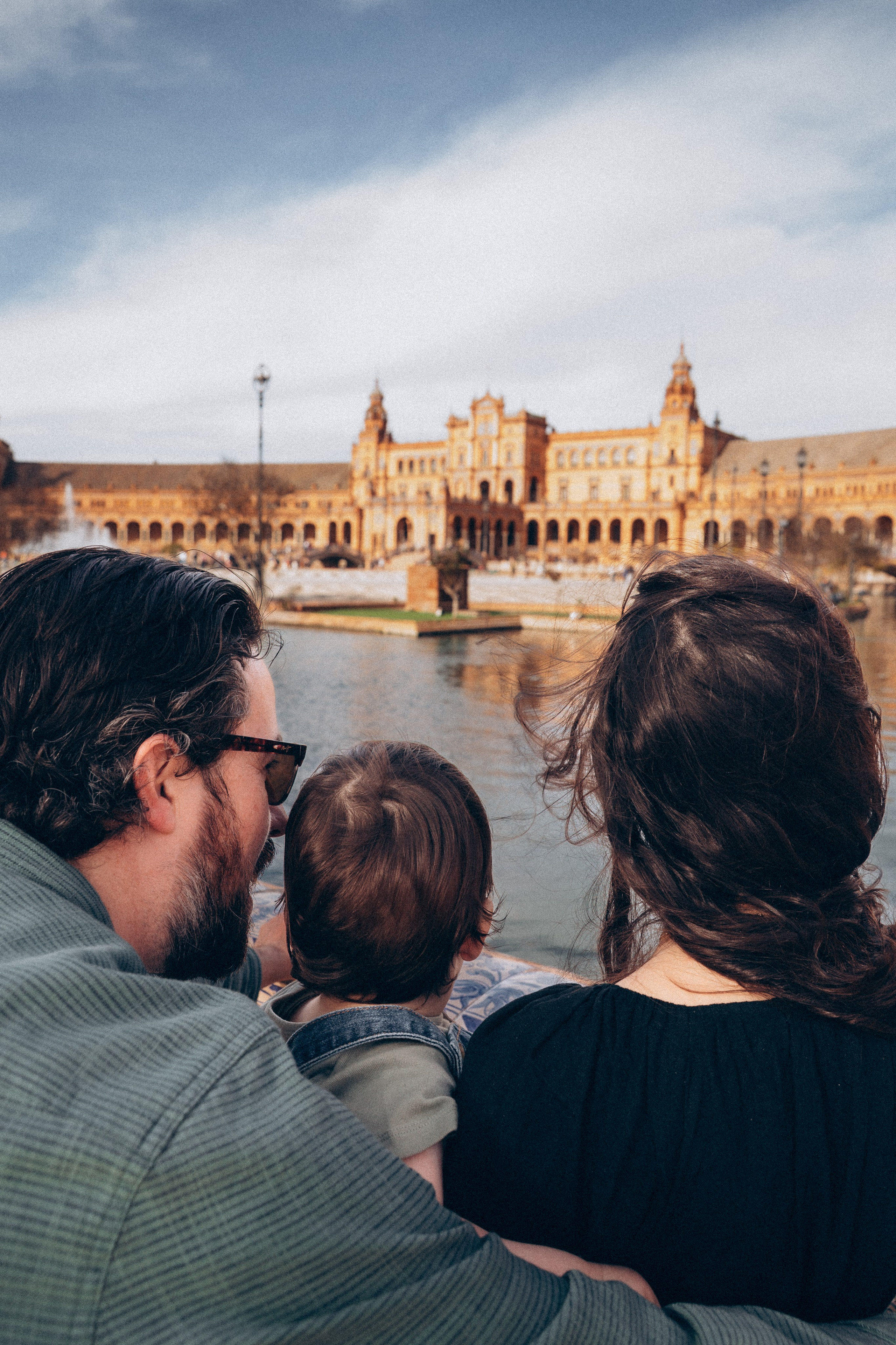 Familia contemplando la icónica Plaza de España en Sevilla, España — capturando un momento tranquilo y reflexivo mientras admiran la arquitectura y disfrutan juntos de este entorno histórico andaluz.