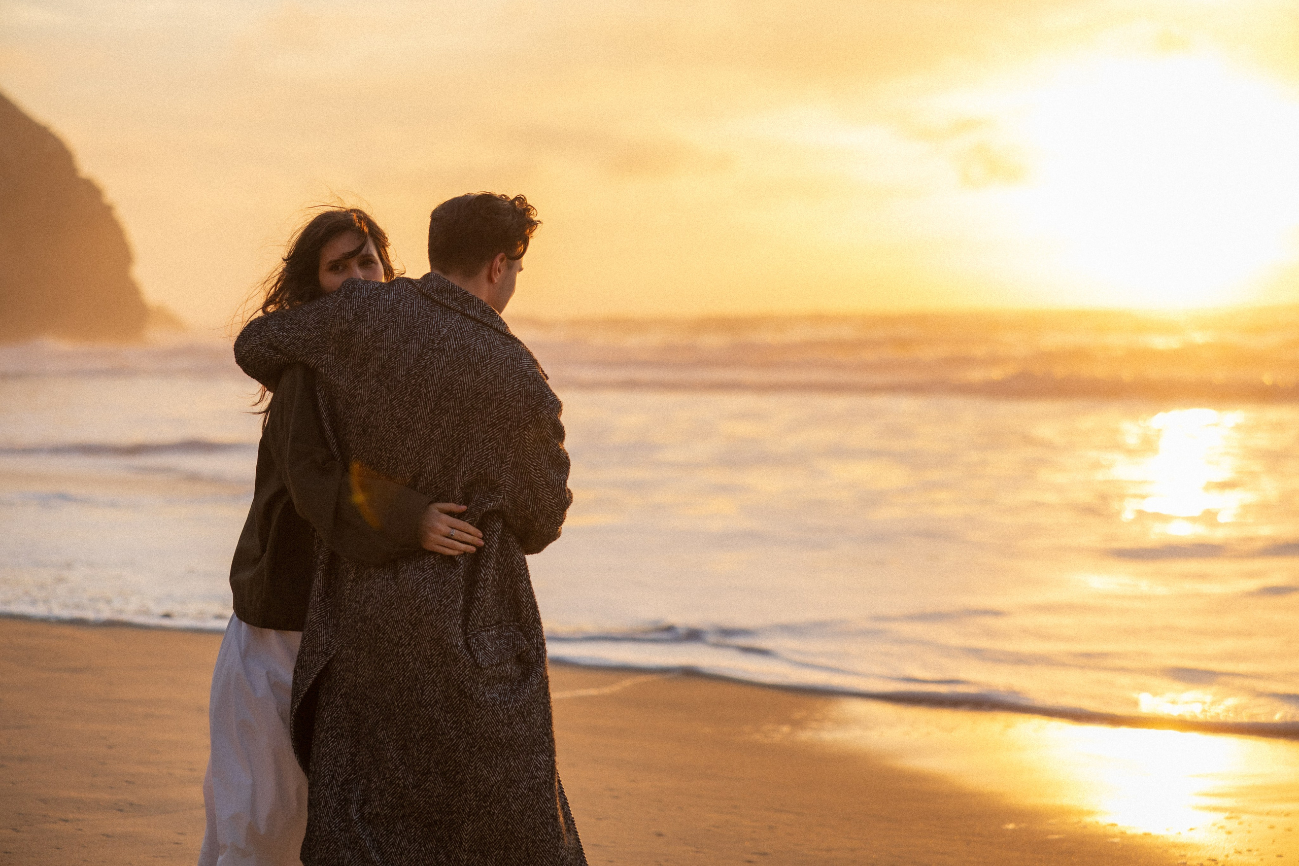 Couple holding hands and walking through a picturesque coastline in Portugal.