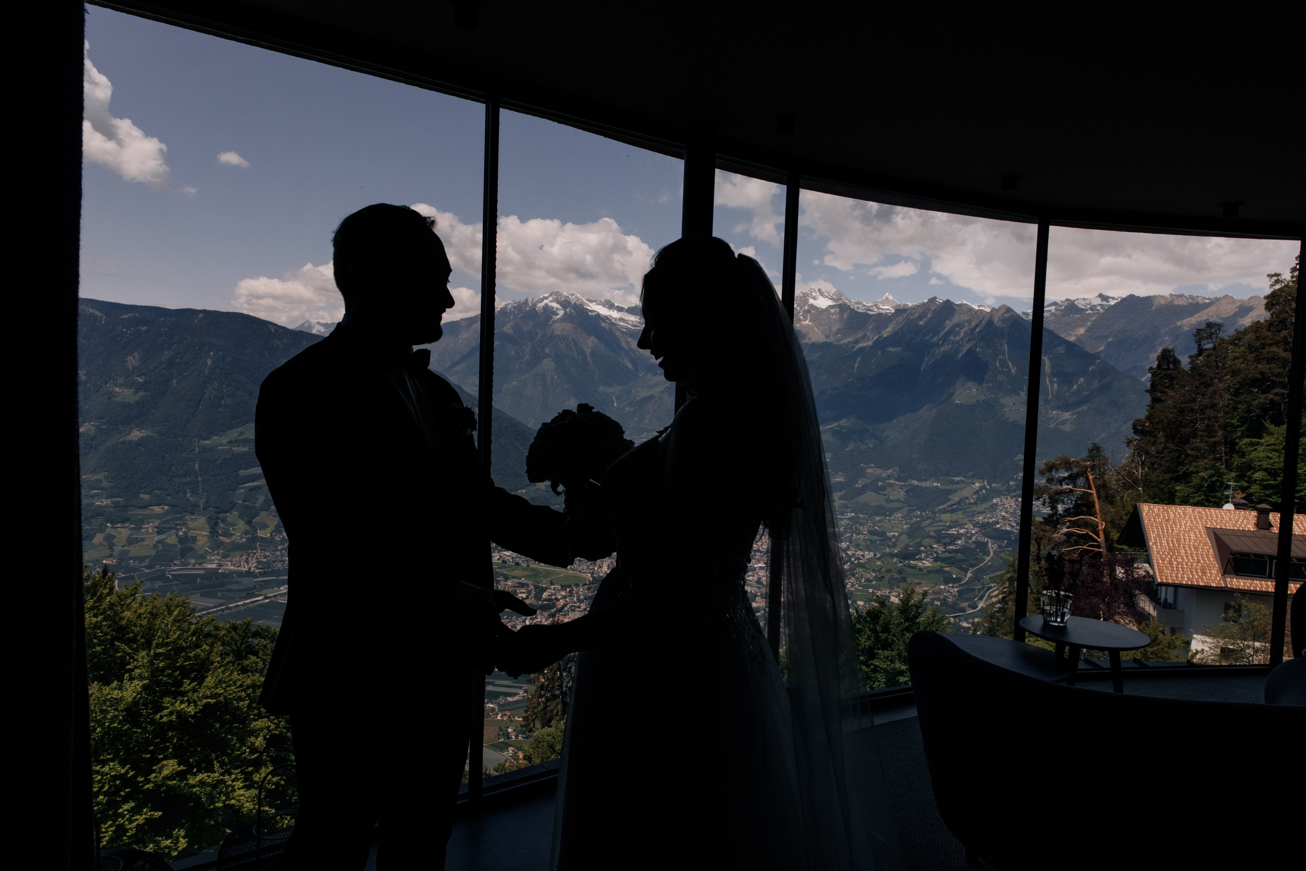 Die Silhouetten des Bräutigams und der Braut, die sich verliebt anschauen, vor der majestätischen Bergkulisse.