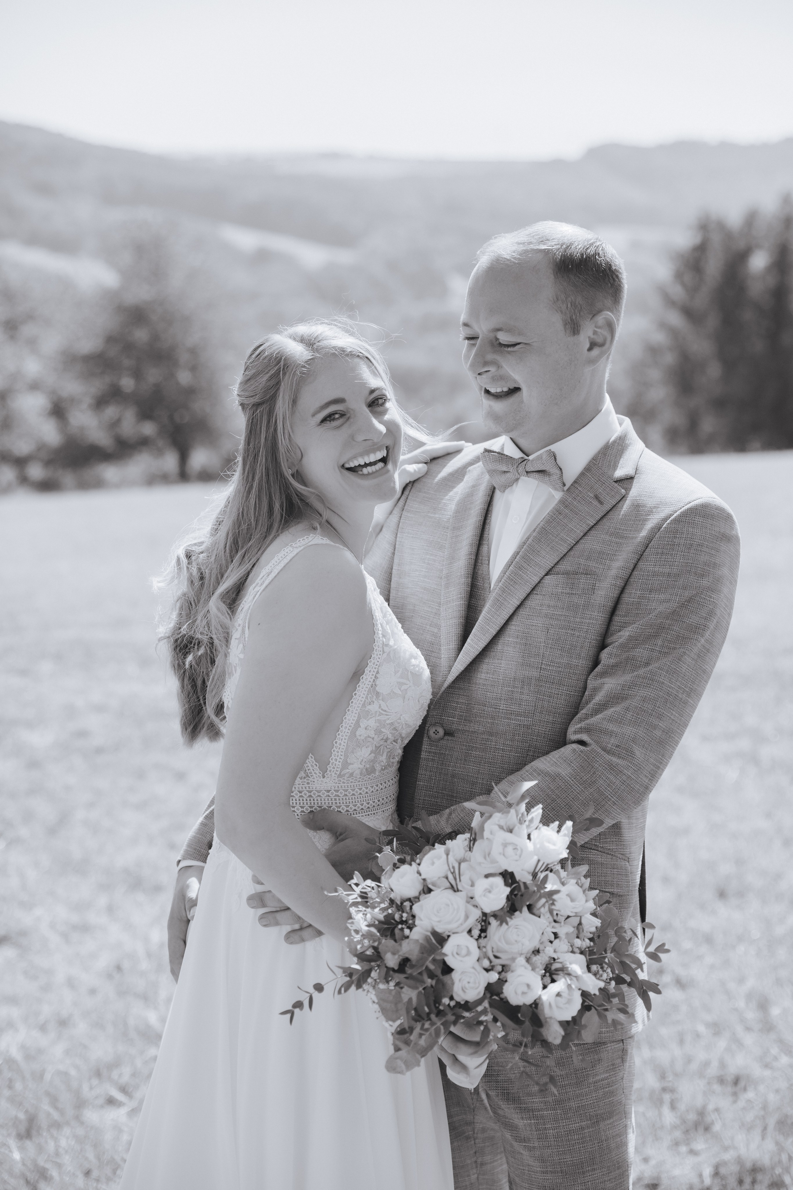 Bräutigam schaut verliebt die Braut an, während sie lächelnd in die Kamera blickt.