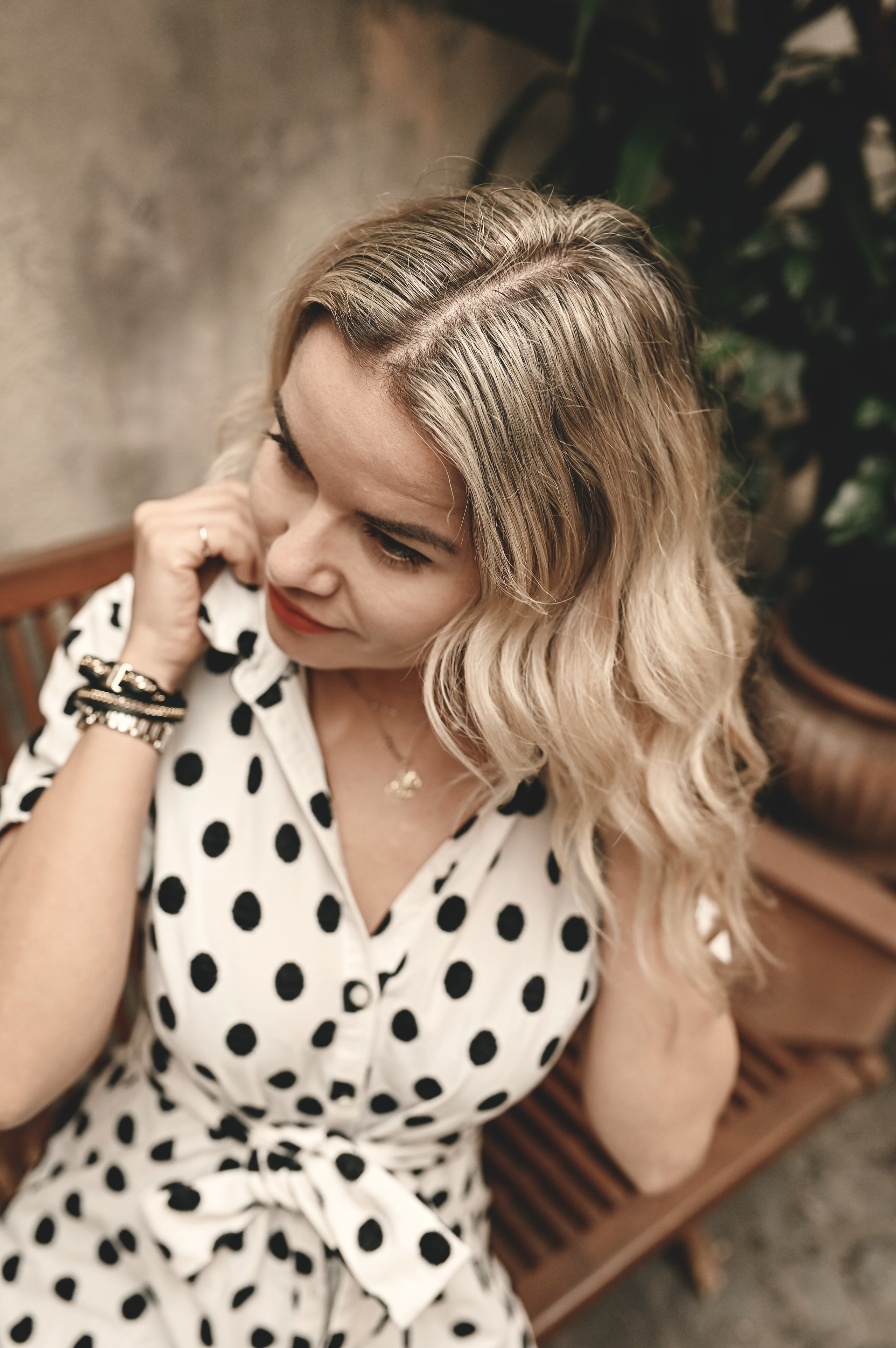 Portrait of a woman in polka-dot dress, smiling thoughtfully while seated on a wooden bench in Rome