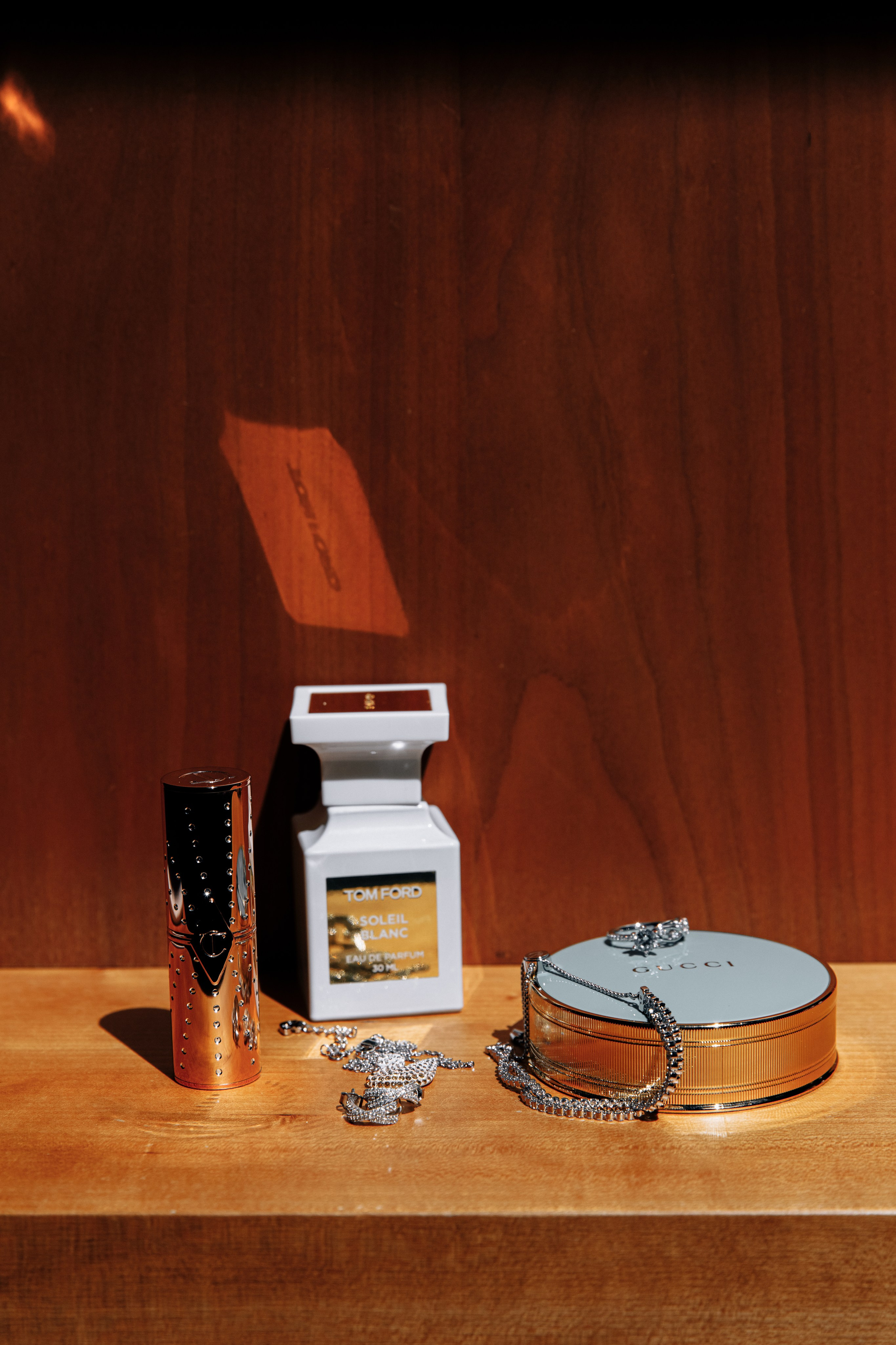 Details des Brautoutfits: Parfüm, Puder, Schmuck und Lippenstift. Elegante Accessoires, die den Look der Braut vervollständigen.