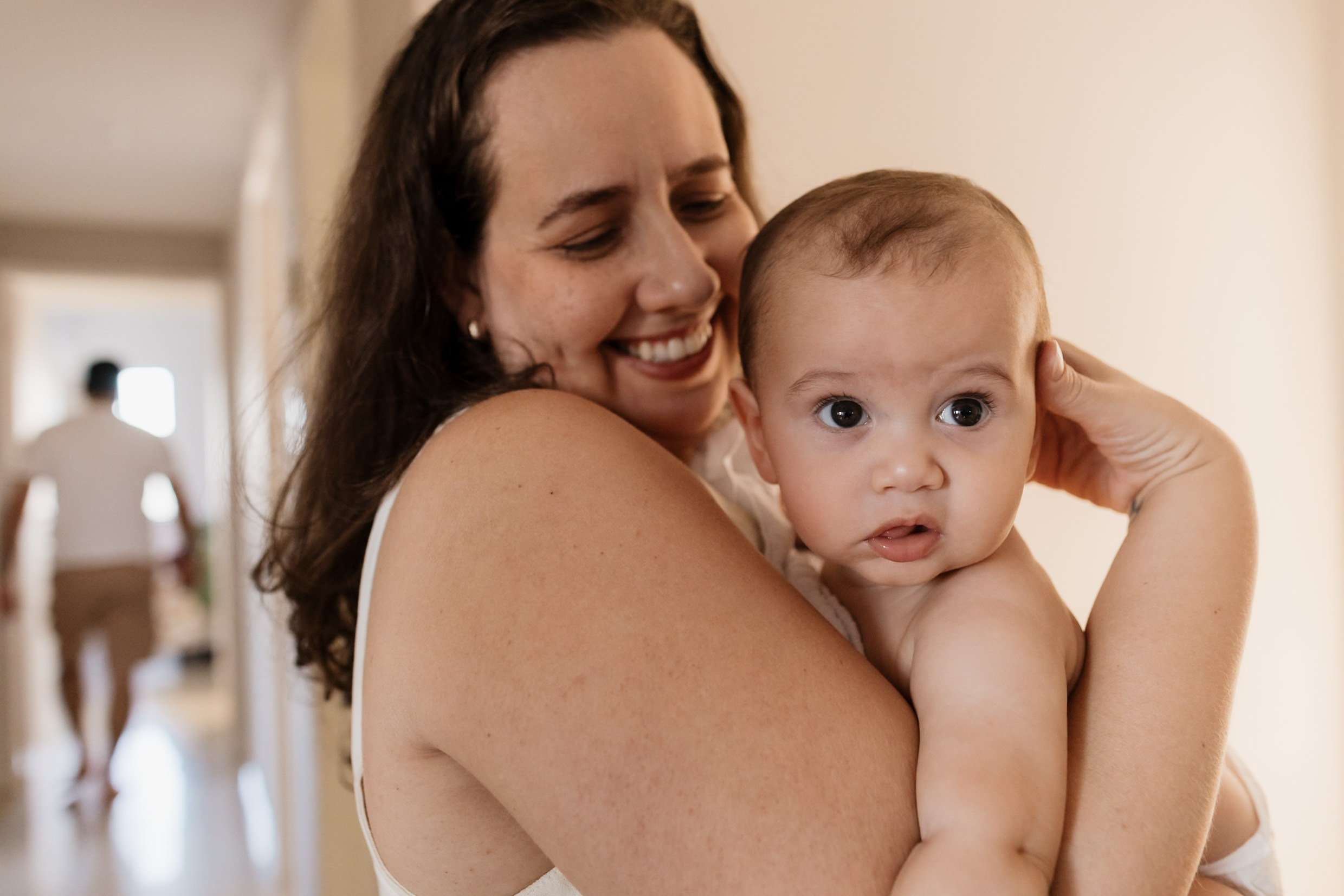 Mãe e bebê em cena afetiva durante ensaio em casa.