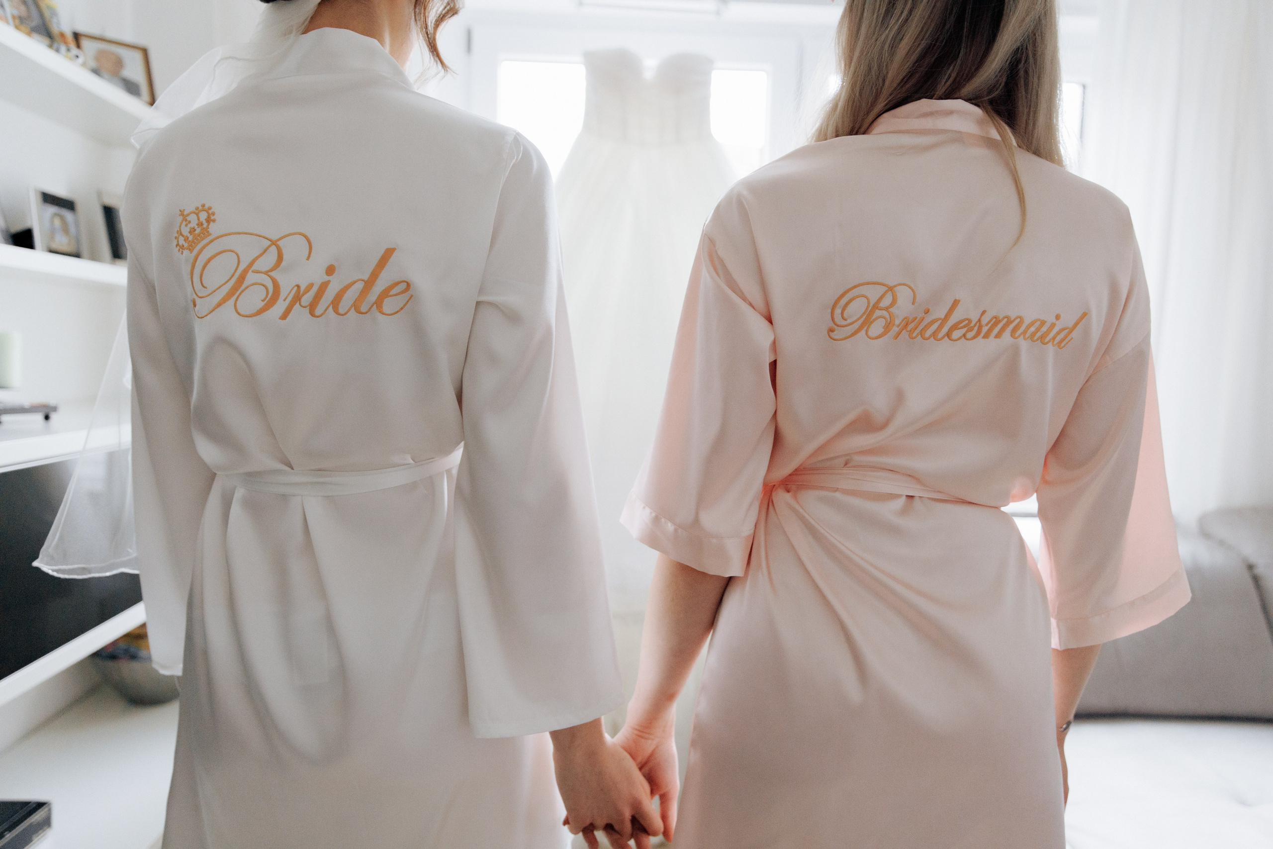 Die Braut und ihre Trauzeugin stehen in Morgenmänteln mit den Aufschriften "Bride" und "Bridesmaid".