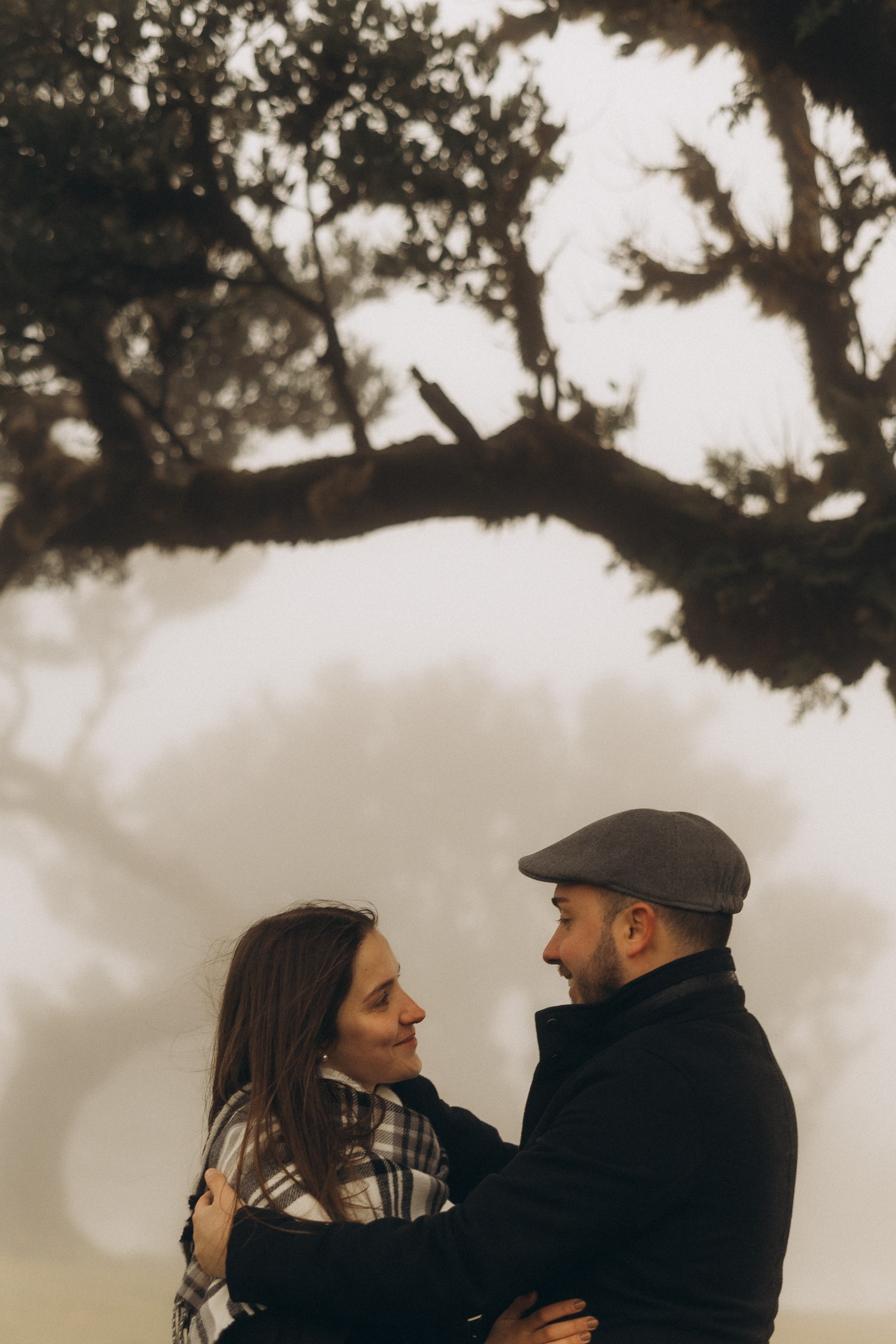 Couple photoshoot in Fanal Forest Madeira PortugalA romantic couple standing amidst the ancient laurel trees of Fanal Forest, Madeira, surrounded by a mystical fog that adds an ethereal touch to the scene