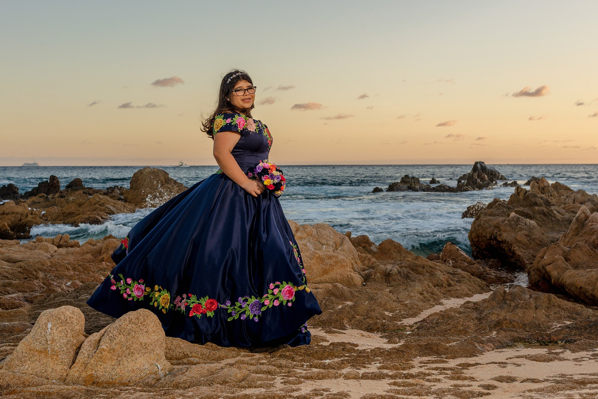 XV años photoshoot in Cabo San Lucas – quinceañera wearing a blue embroidered Mexican dress at Playa Las Viudas, captured at golden hour with the Pacific Ocean as backdrop