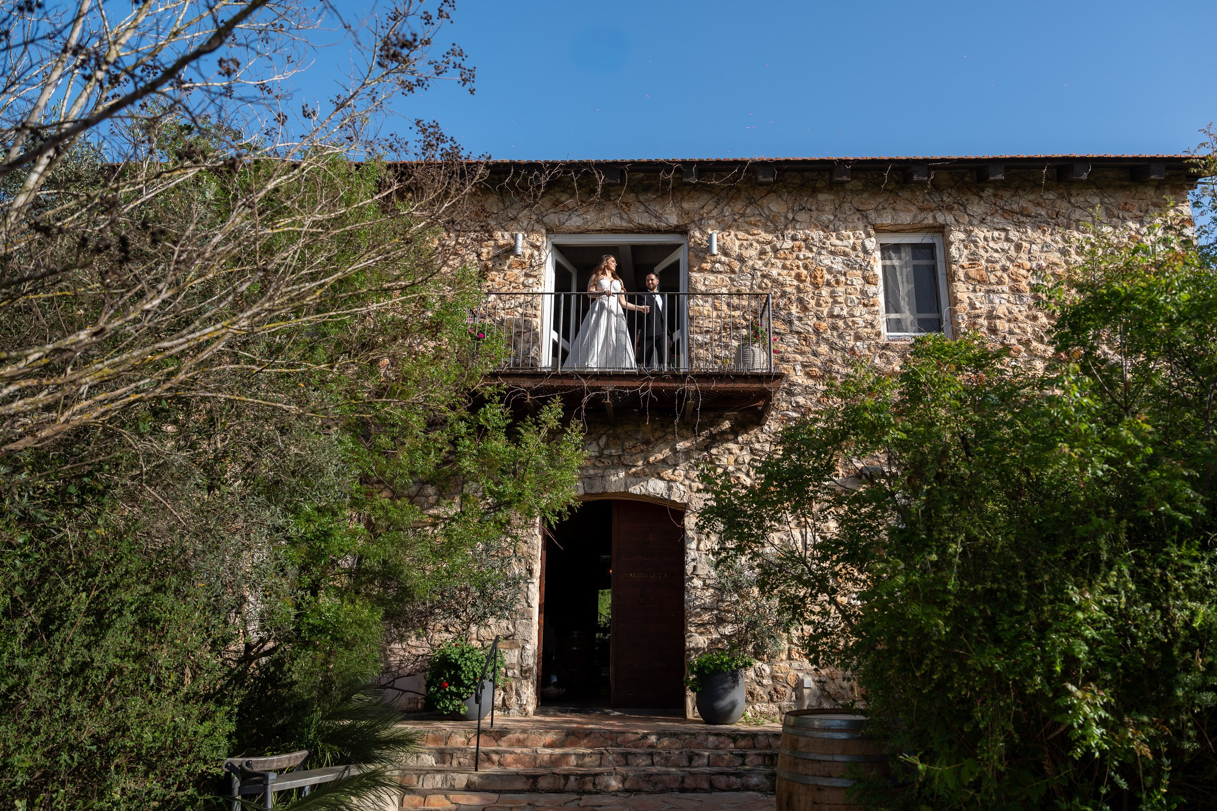 Tzipi and Ron standing on a balcony of the stone building during their photoshoot at Amphorae Winery