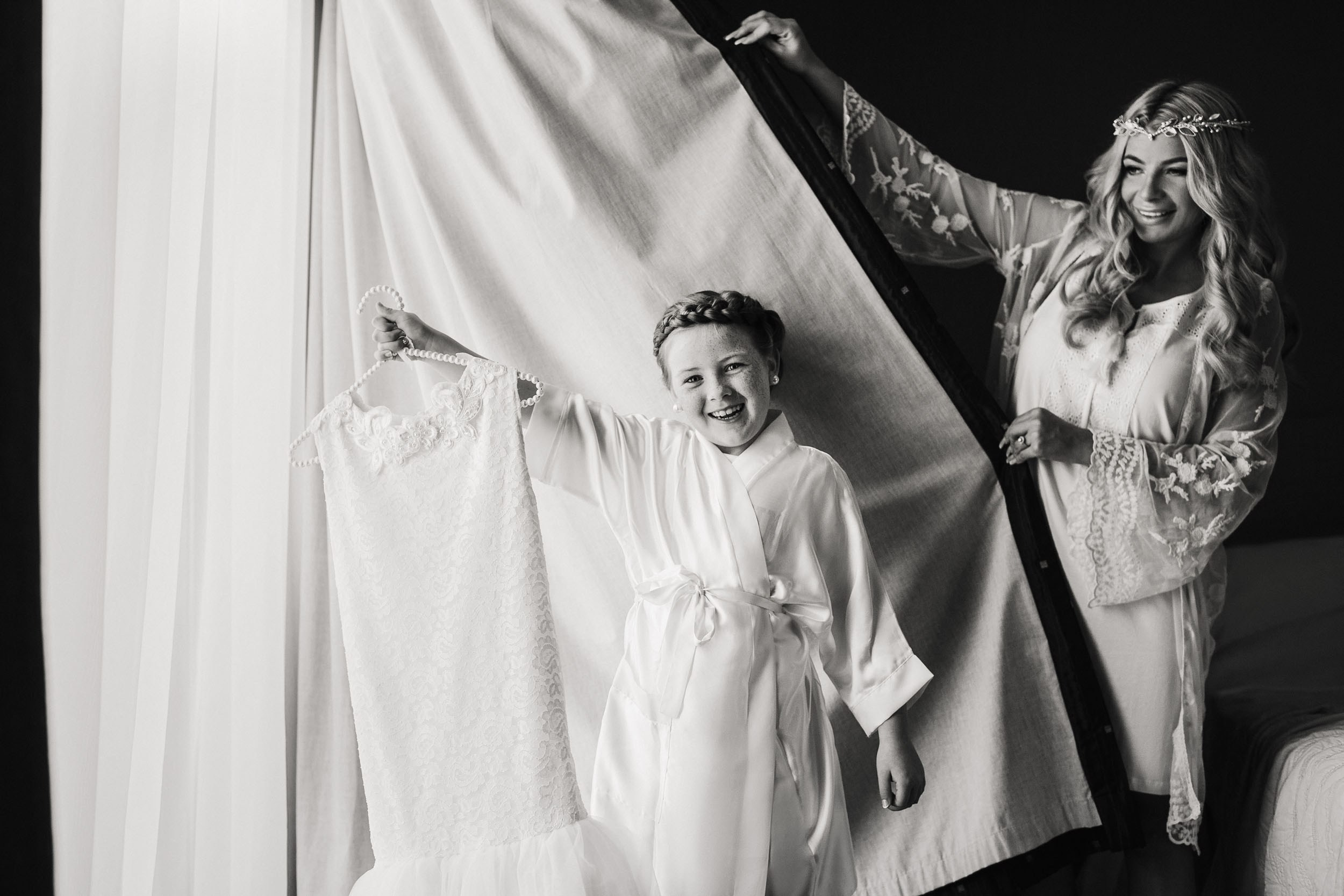 Bride and cute girl are posing in front of the window
