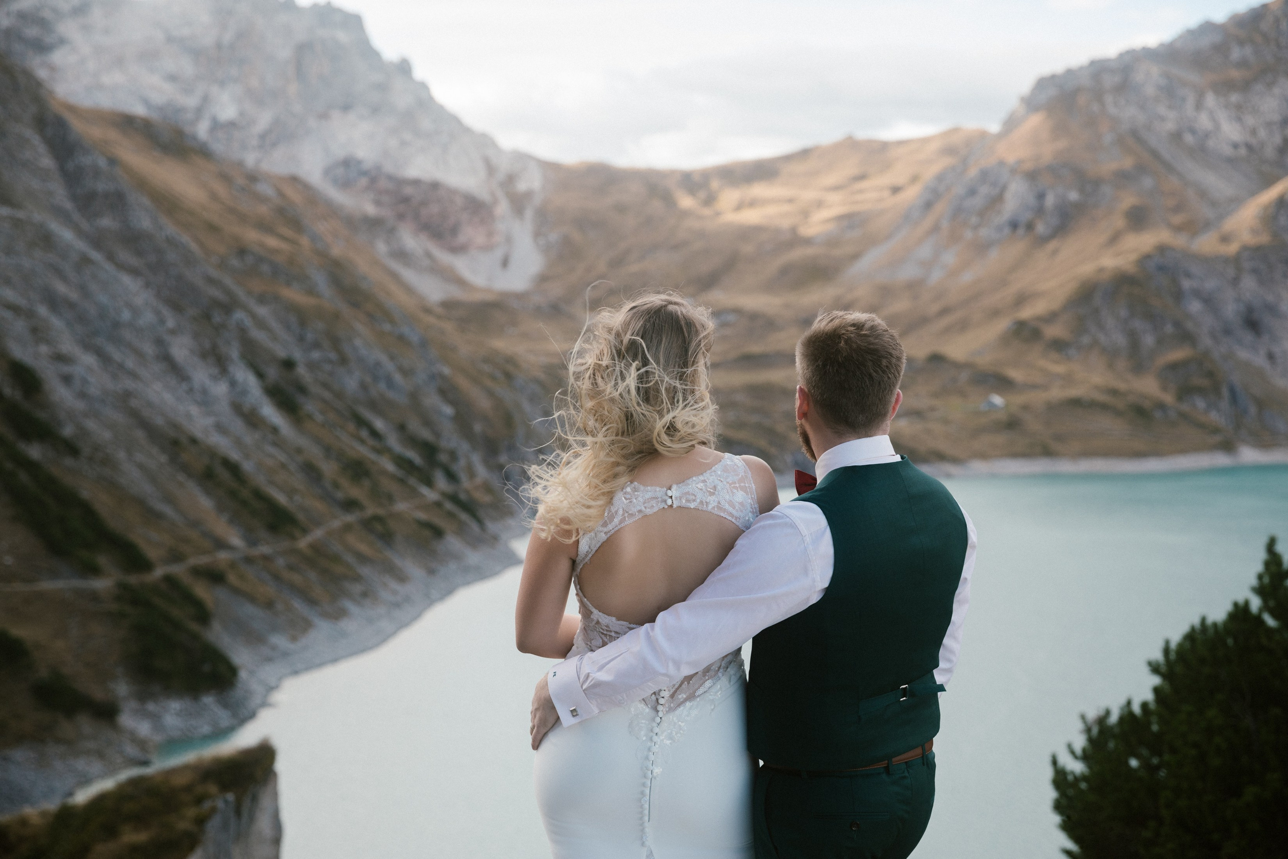 Brautpaar blickt auf türkisblauen Lünersee bei alpiner Hochzeitsfotografie