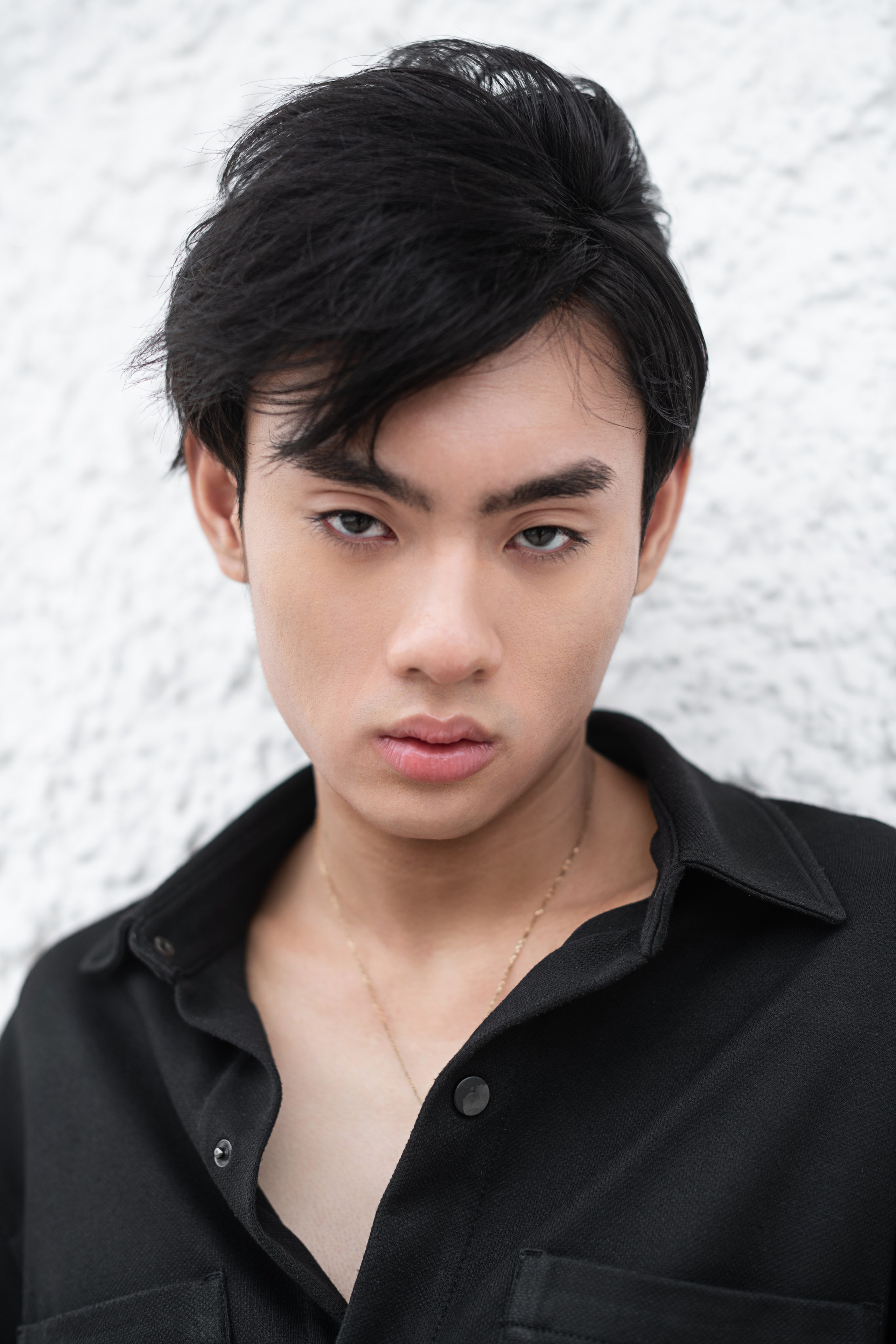 Black and white portrait of a male model with a contemplative expression and minimalist styling in a refined Singapore setting.