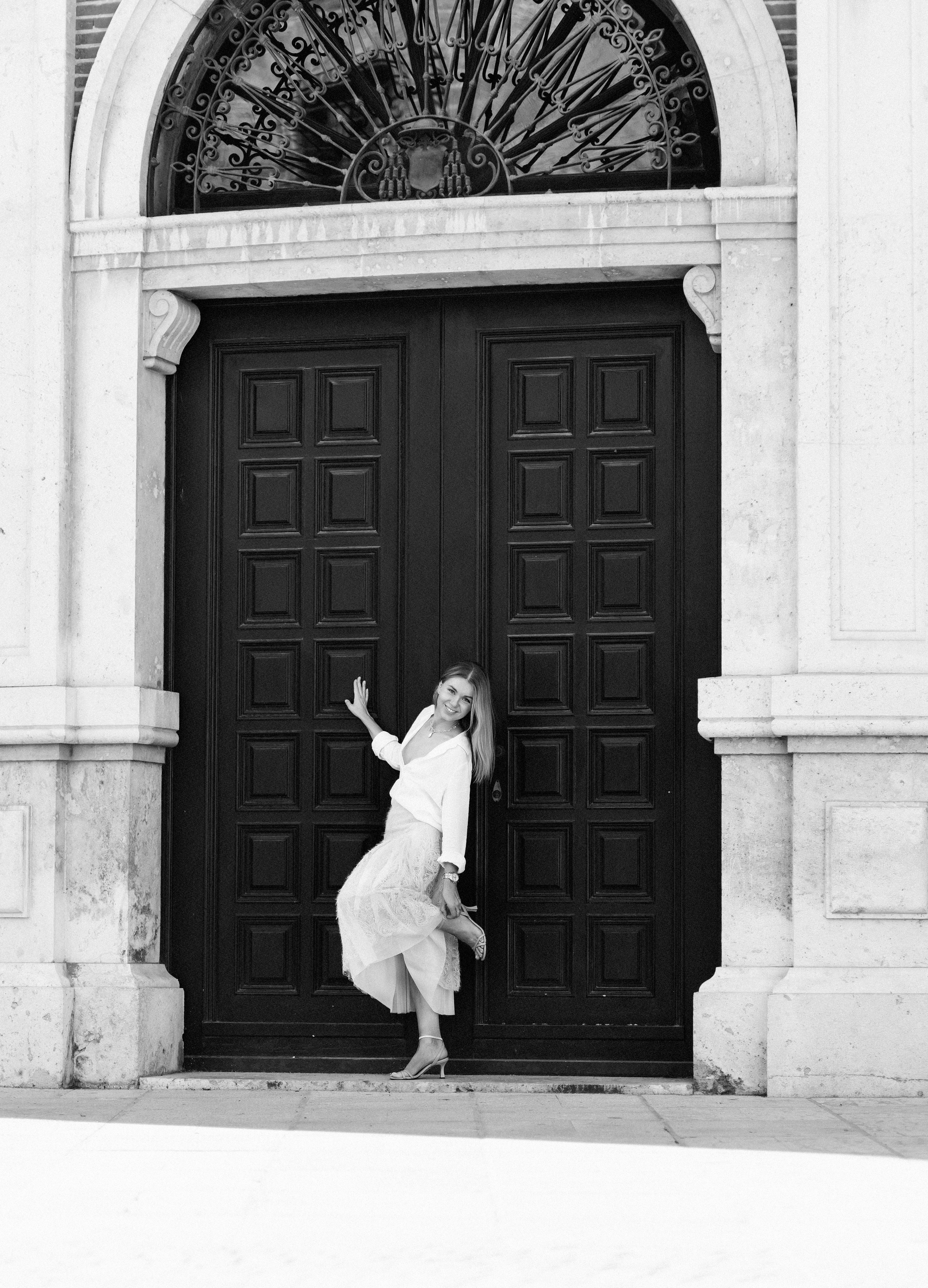 Креативная женская портретная фотосессия в Валенсии, Испания, с радостной женщиной в летящем наряде у элегантного исторического входа — вдохновение для выразительных и художественных женских фотосессий в Испании.