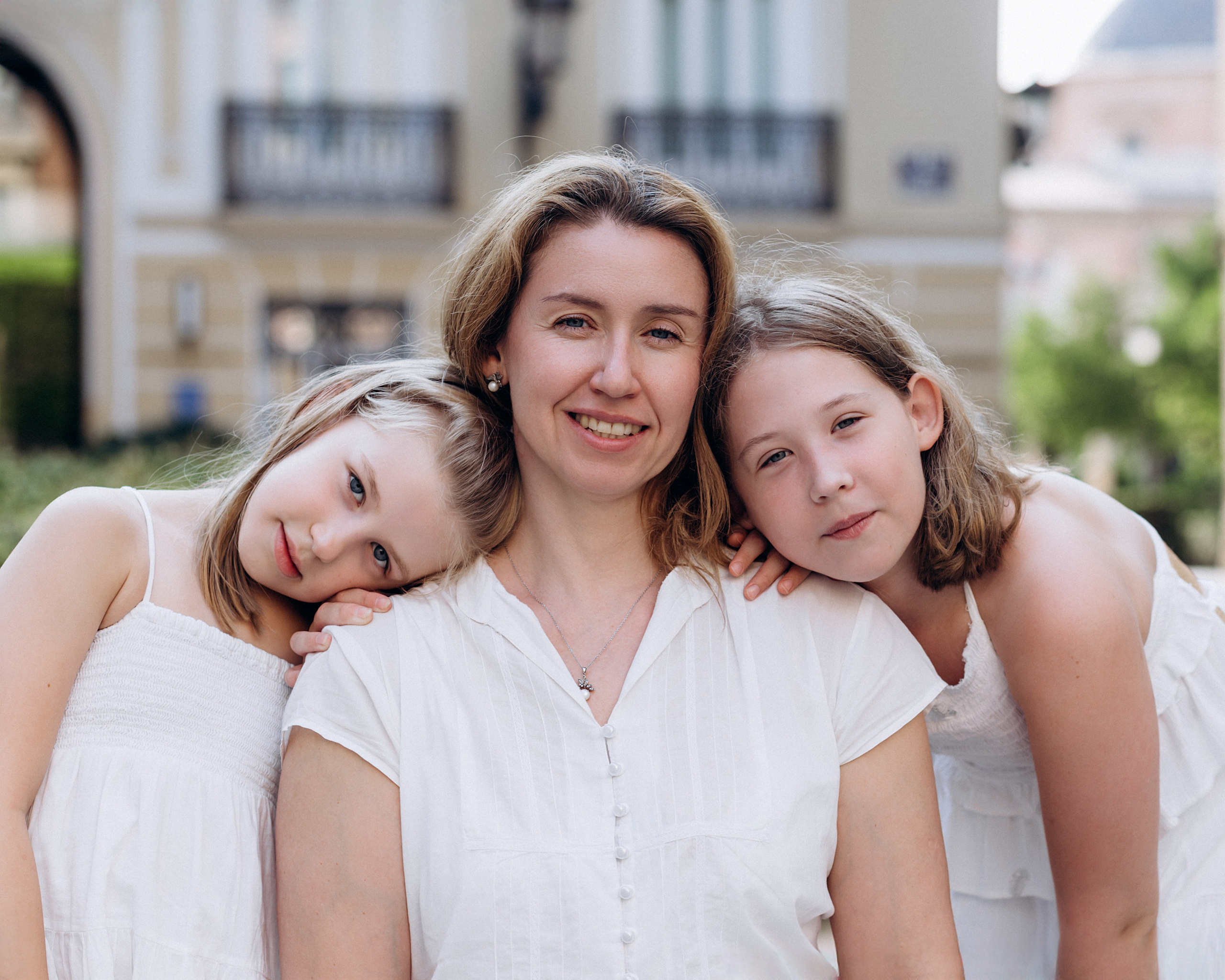 Retrato familiar en primer plano capturado en Valencia, España, con una madre sonriente abrazada por sus dos hijas — un momento íntimo ideal para quienes buscan sesiones familiares emocionales y naturales en Valencia y España.