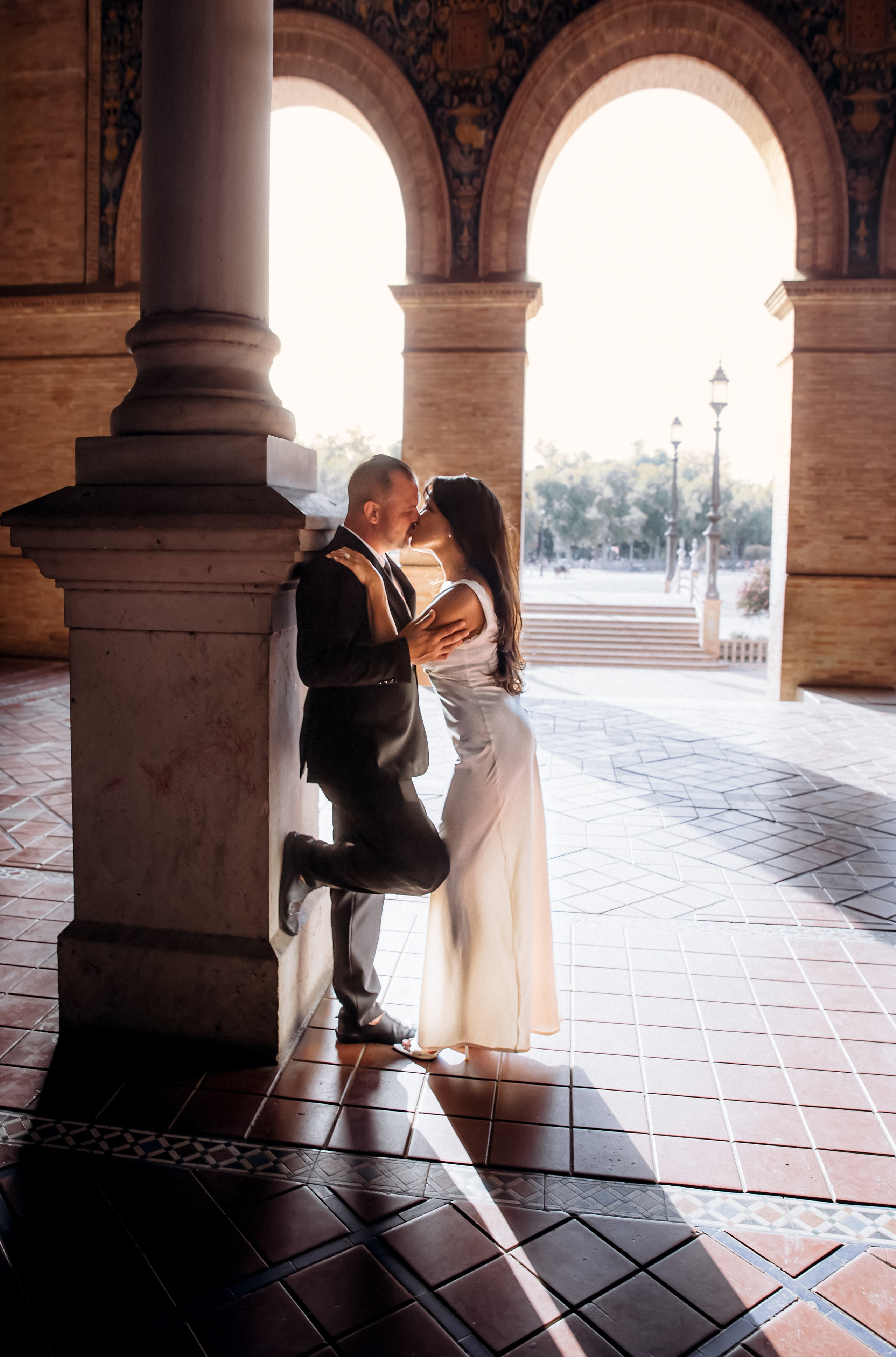 Intimate wedding moment captured in Madrid, Spain — the couple shares a romantic embrace under elegant stone arches bathed in soft natural light. A stunning choice for couples searching for timeless and passionate wedding photoshoots in Madrid and throughout Spain.