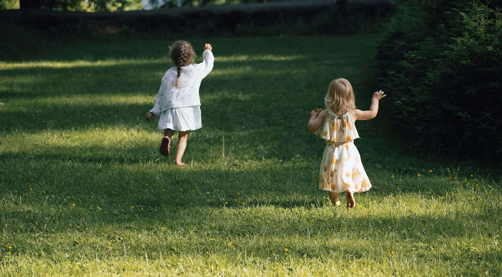 Jenter løper i greset og koser seg.