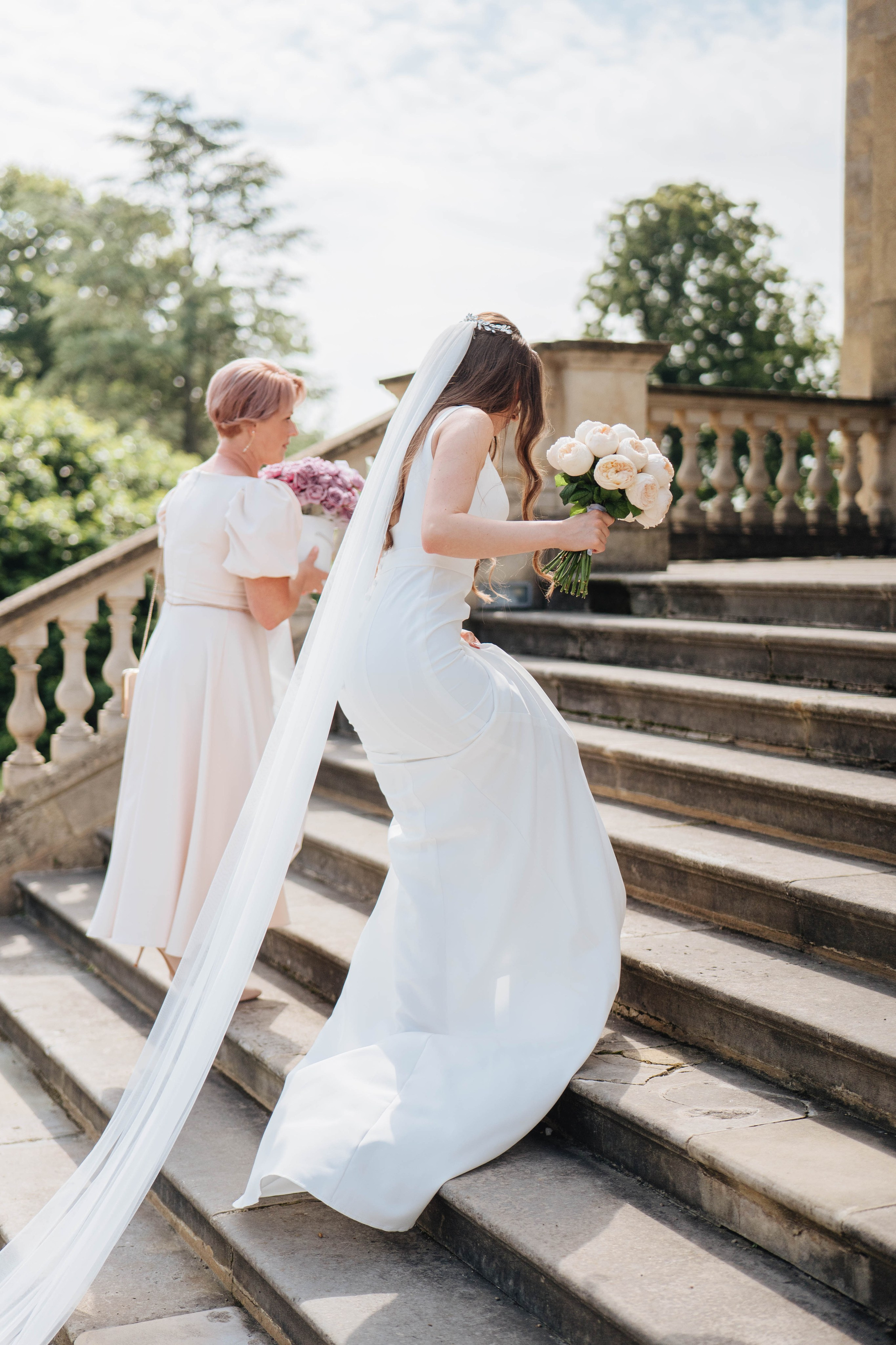 bride entering the venue with large beautiful stairs with her mother