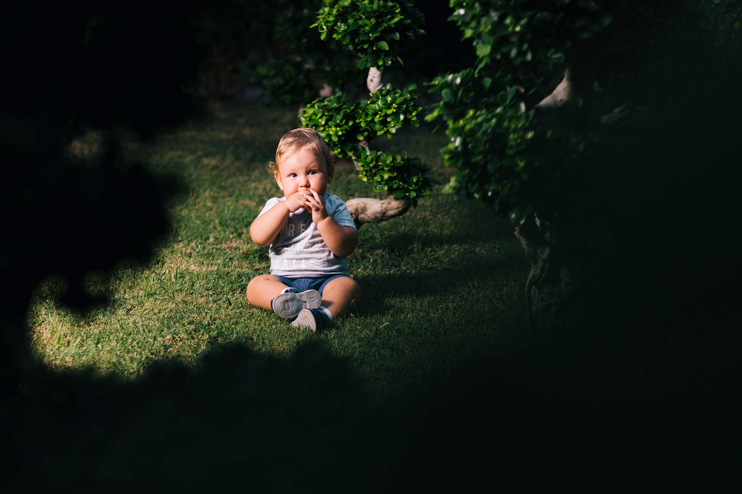baby boy sitting on a grass in the park and curiously glazing 