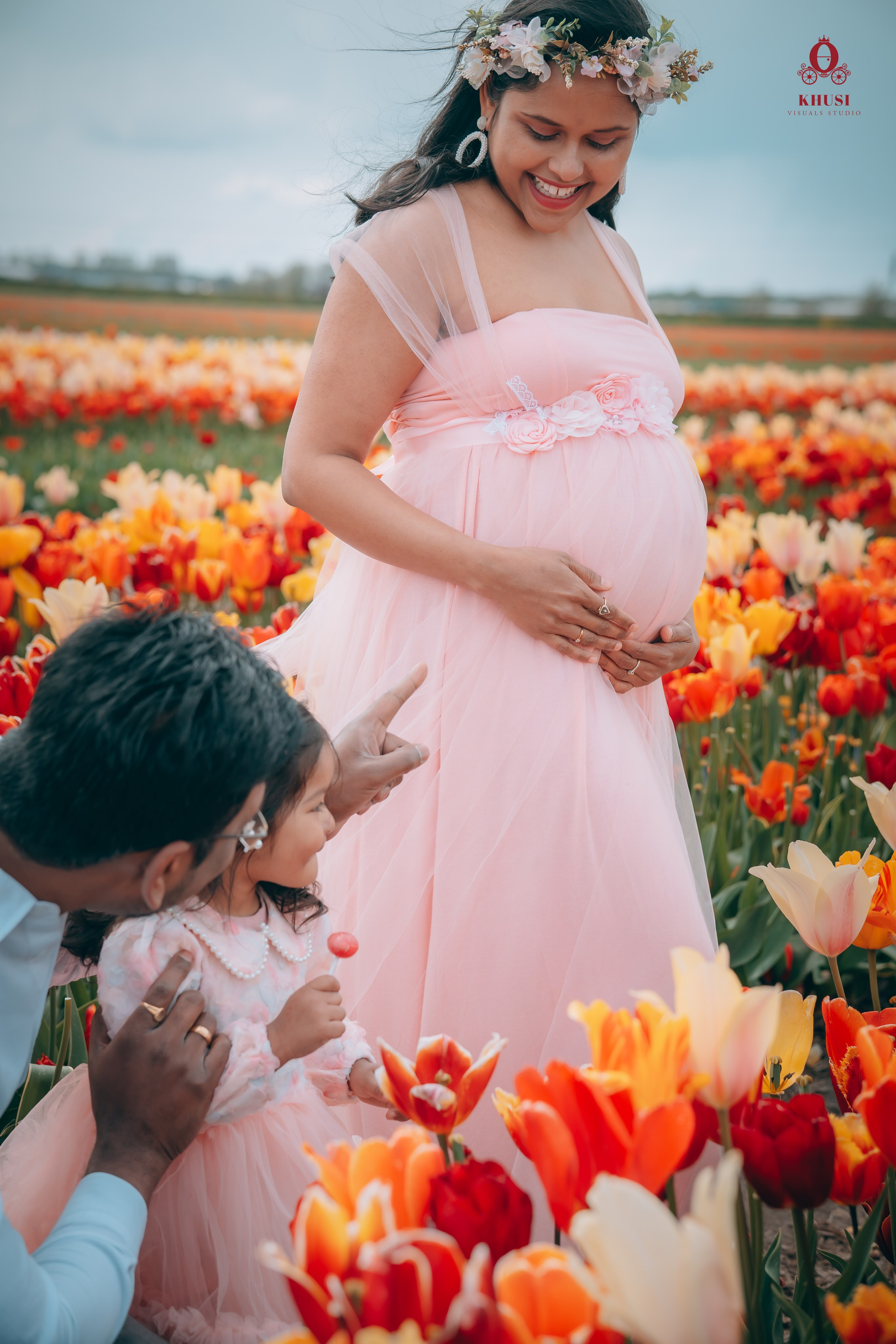 a father pointing fingers to her pregnant wife showing her daughter in a tulip fields in netherlands