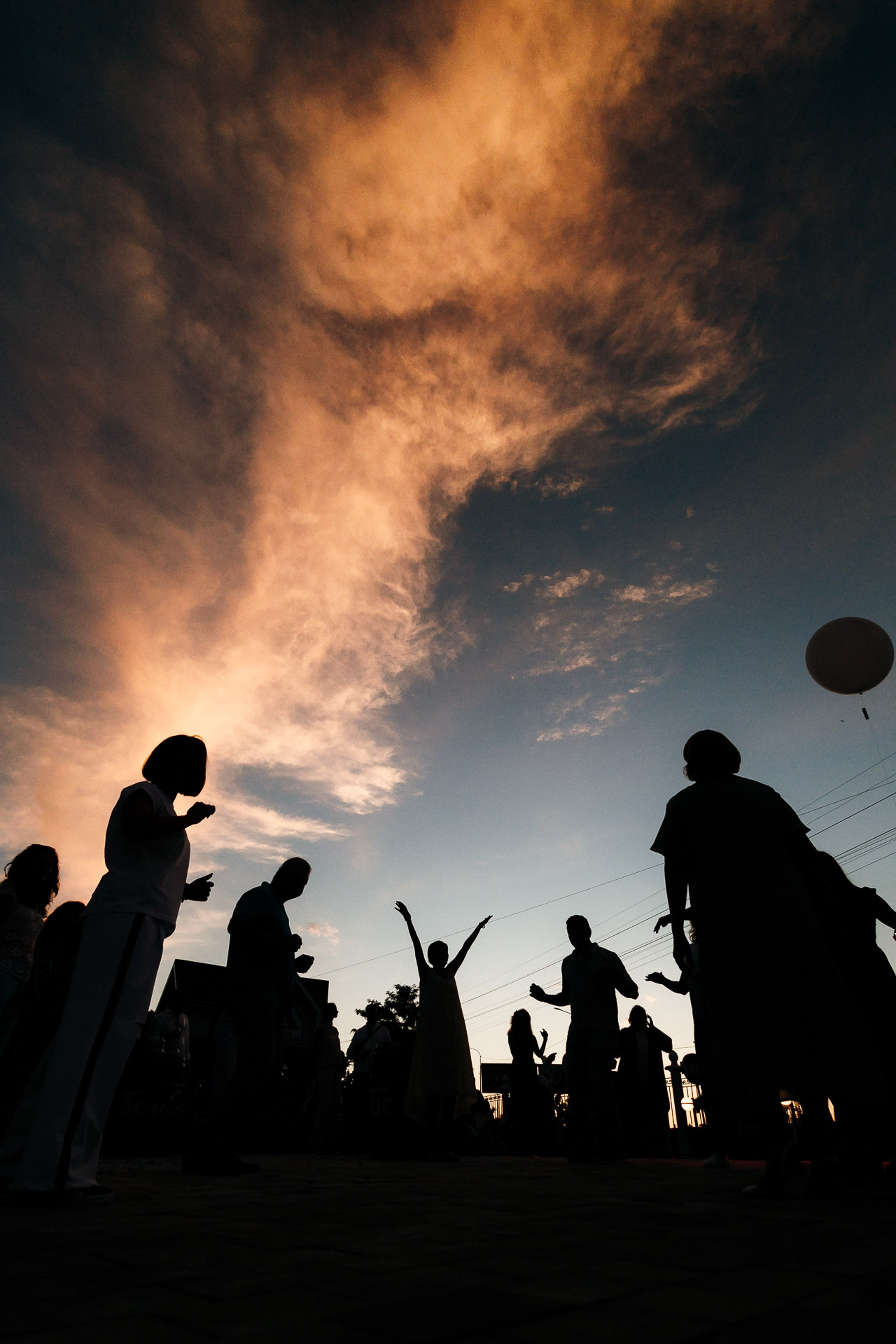 Silhouettes of people under dramatic sky, evening event