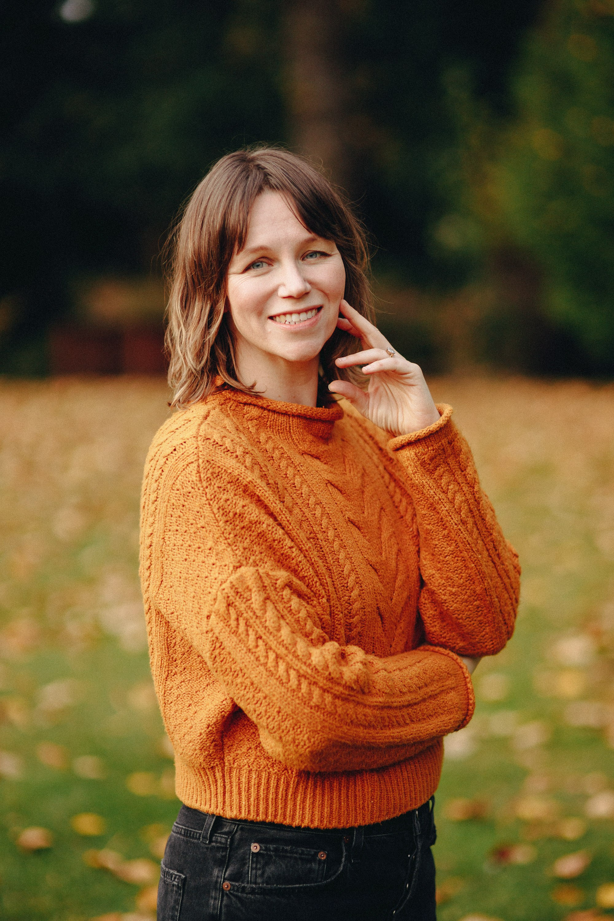 Smiling woman in orange sweater with arms crossed