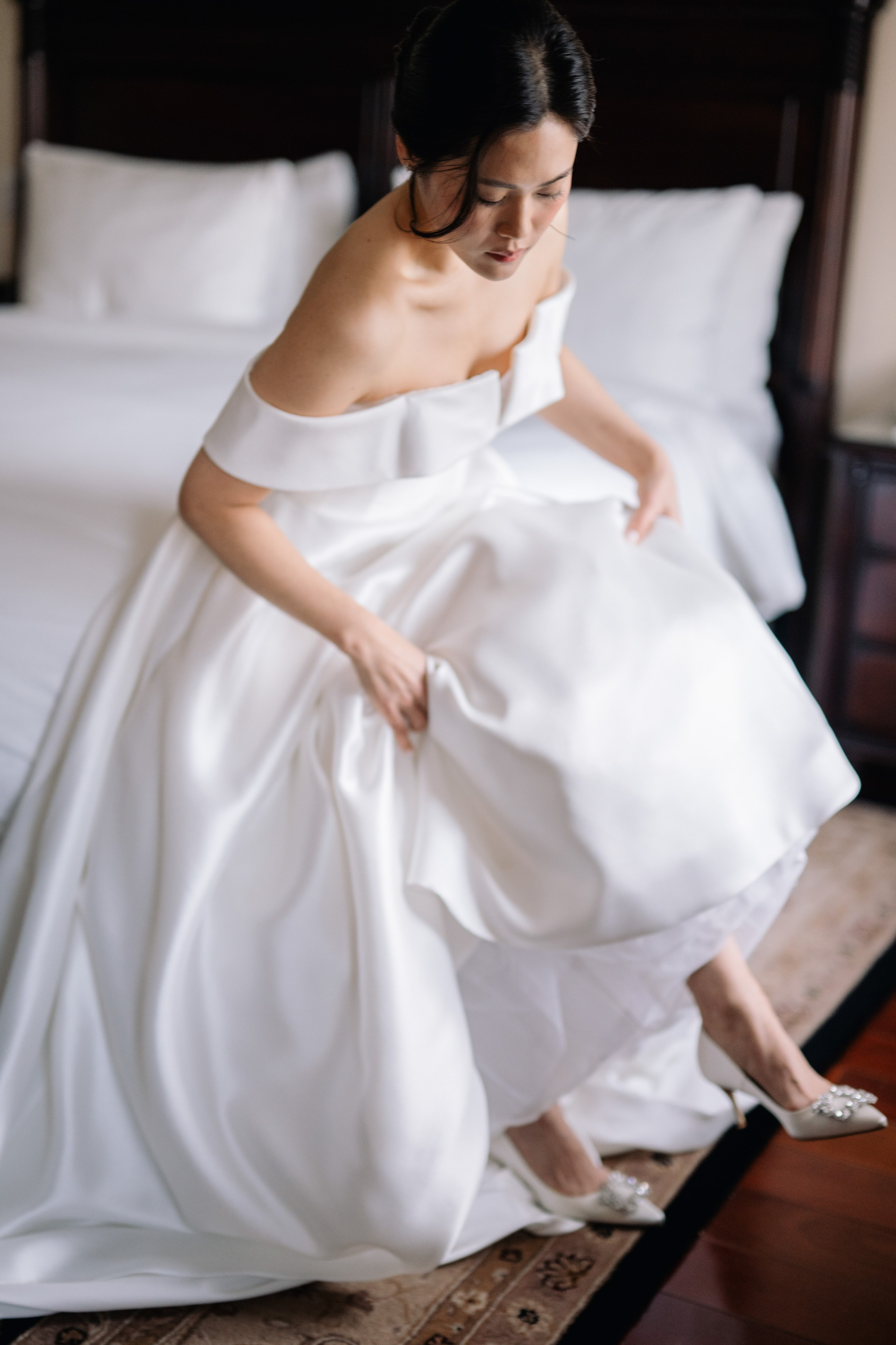 a woman in a white dress is sitting on a bed