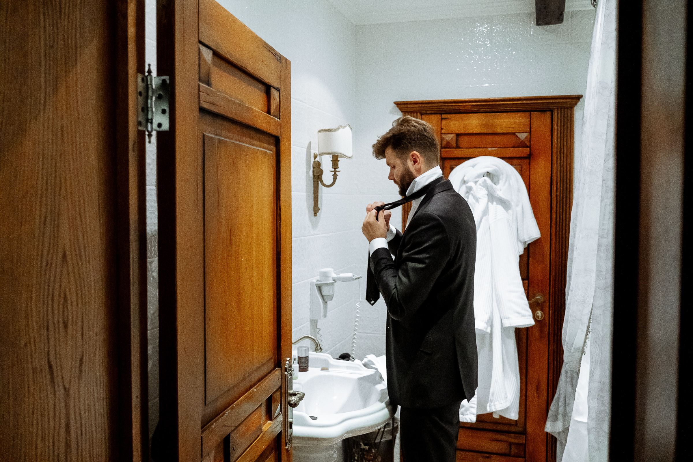 Groom tying tie, by Tanya Bodgan, Bude, Cornwall wedding photographer.