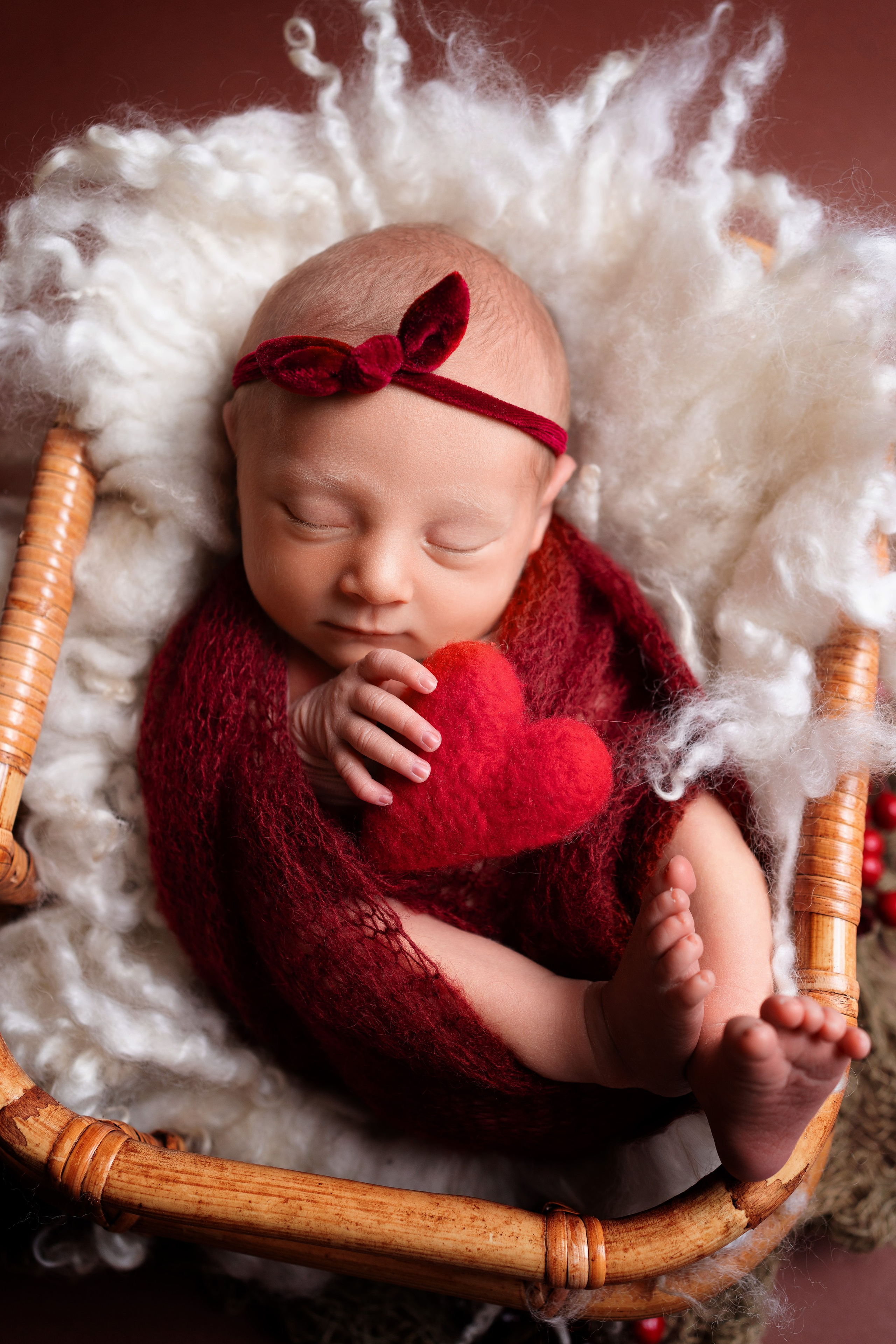 Neugeborenes Mädchen hält ein rotes Herz in den Händen