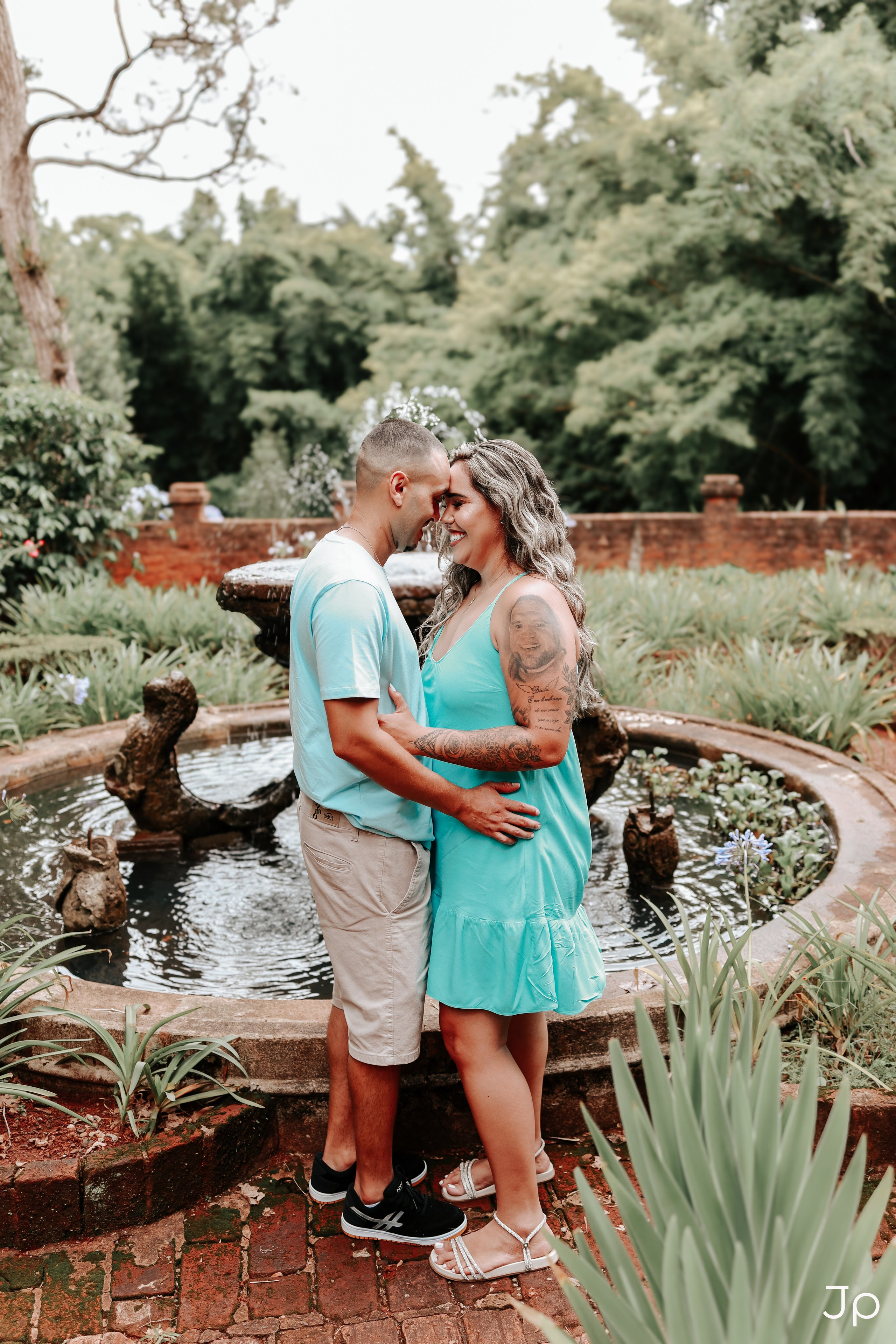 Casal abraçado ao lado de uma fonte, durante ensaio de casal em Pederneiras.