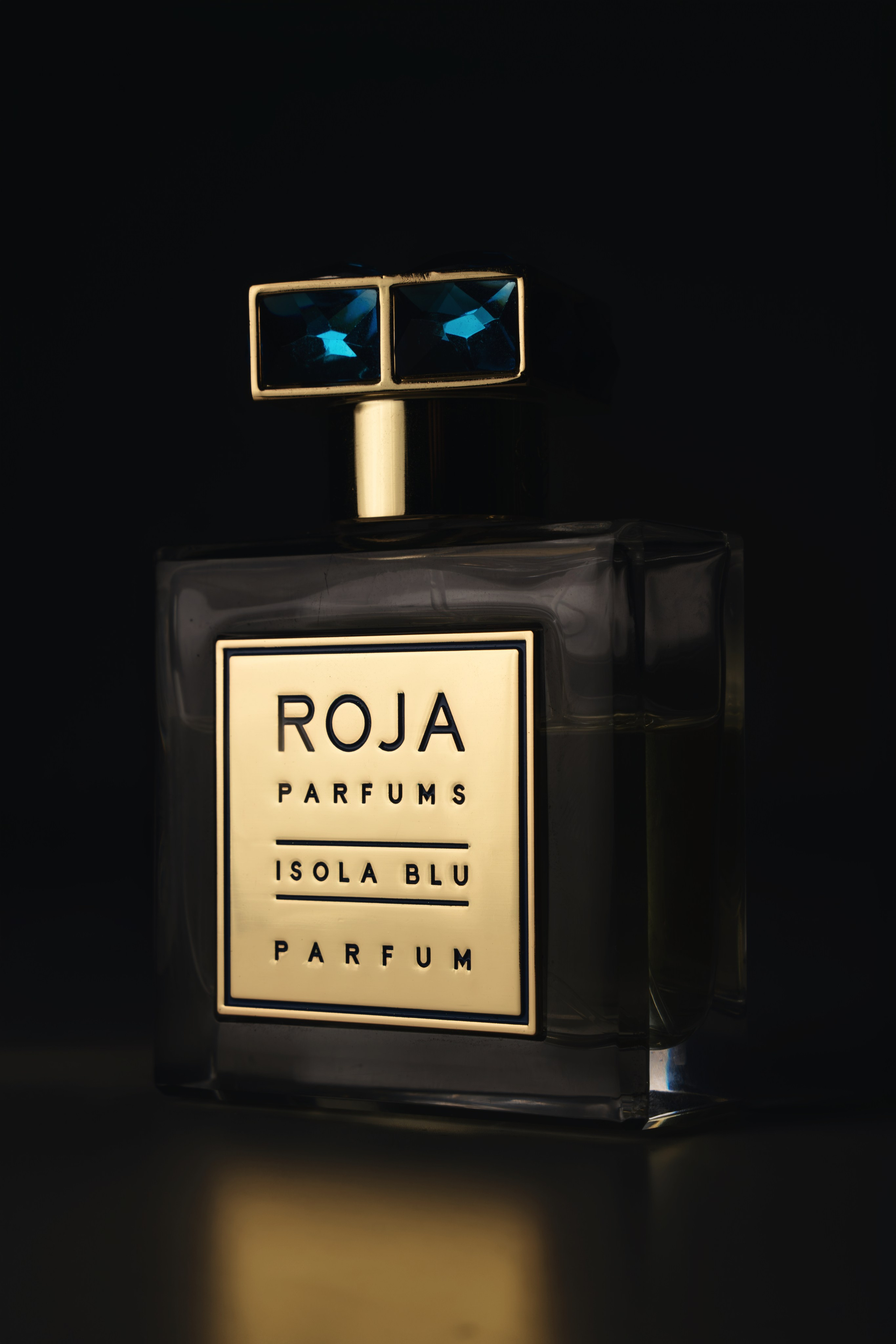 Roja Parfums bottle with gold detailing on black background — premium fragrance still life London.