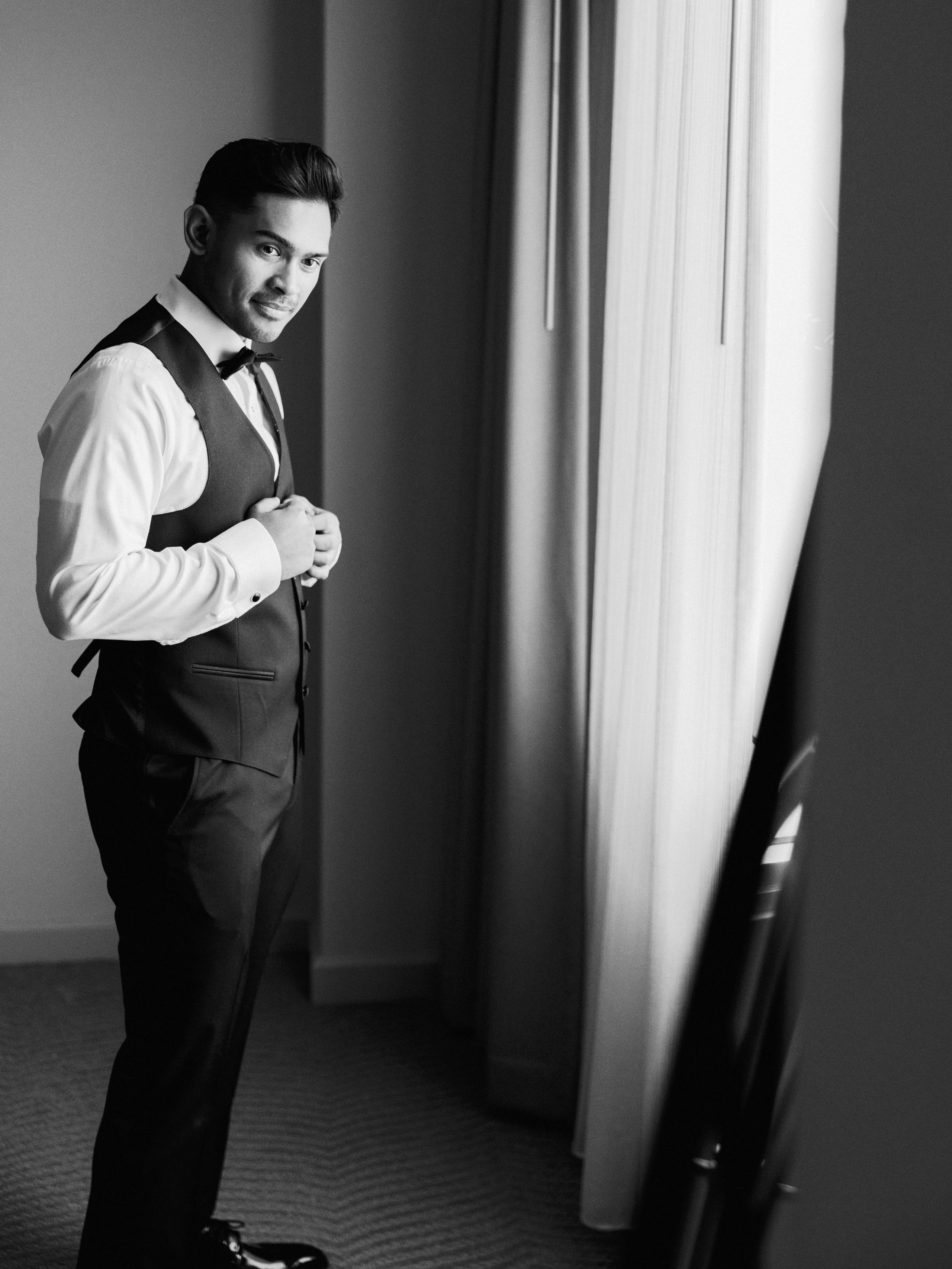 Black-and-white portrait of the groom by a window
