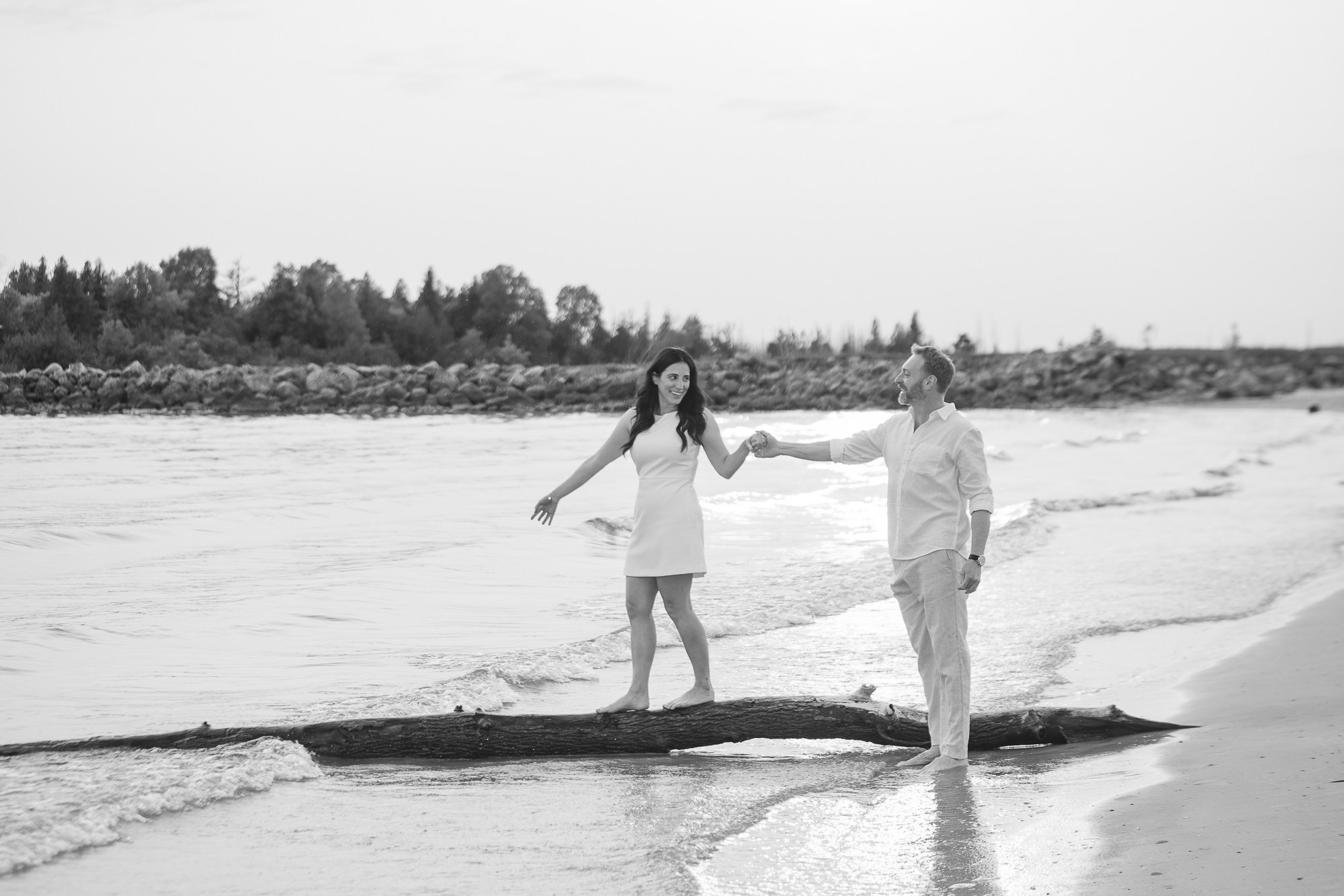 Couple walking hand in hand on a wooden boardwalk by the lake during their engagement photoshoot.