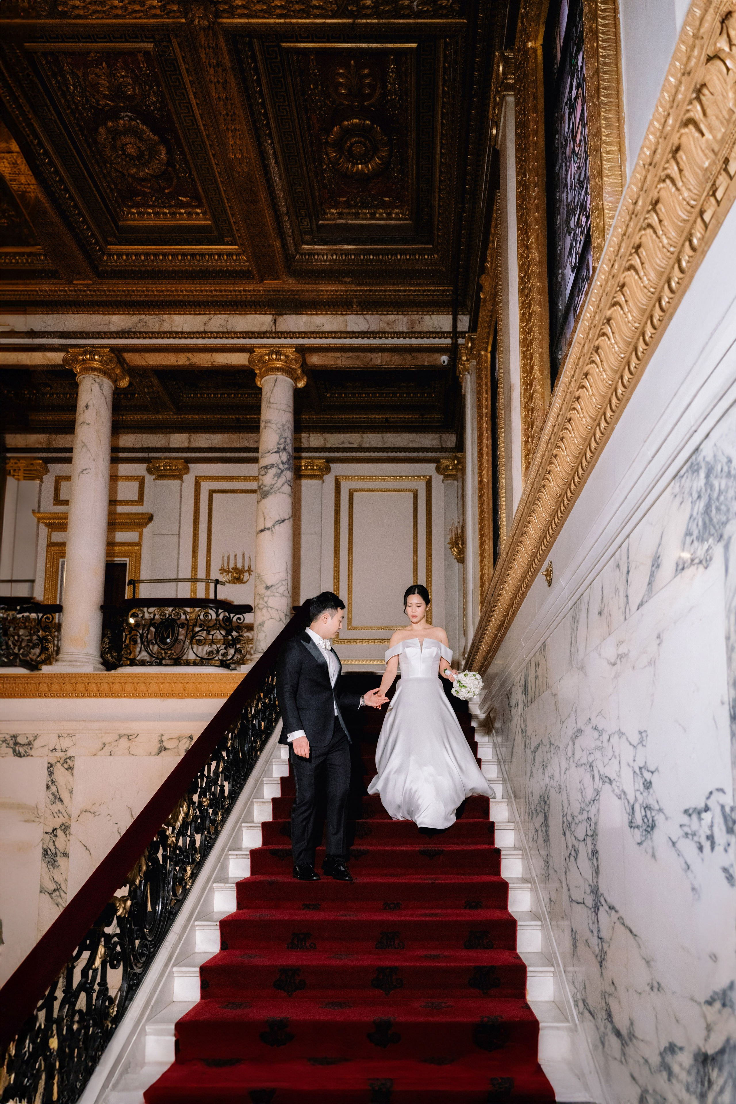 a bride and groom walking down the stairs of a building