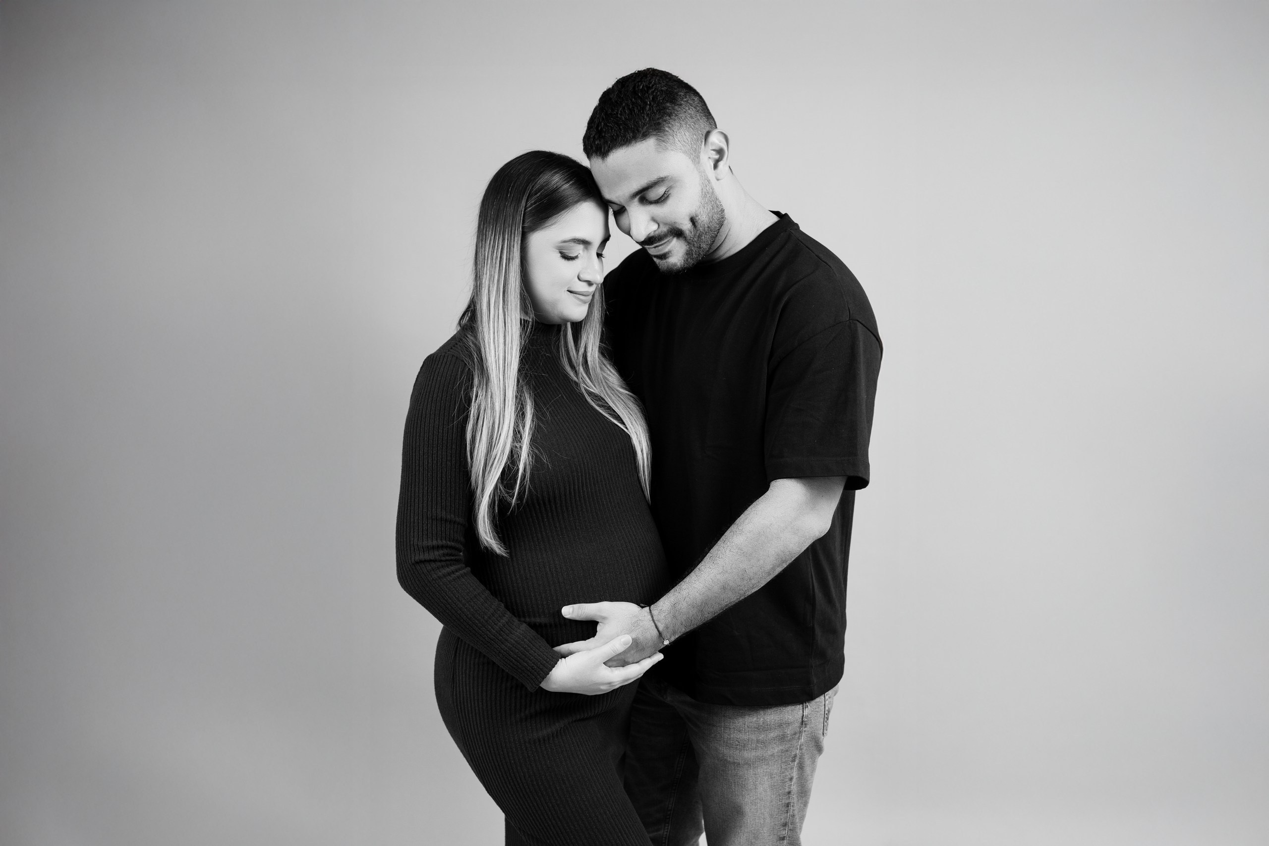 Retrato minimalista de embarazo en fondo neutro en estudio fotográfico en Barranquilla.