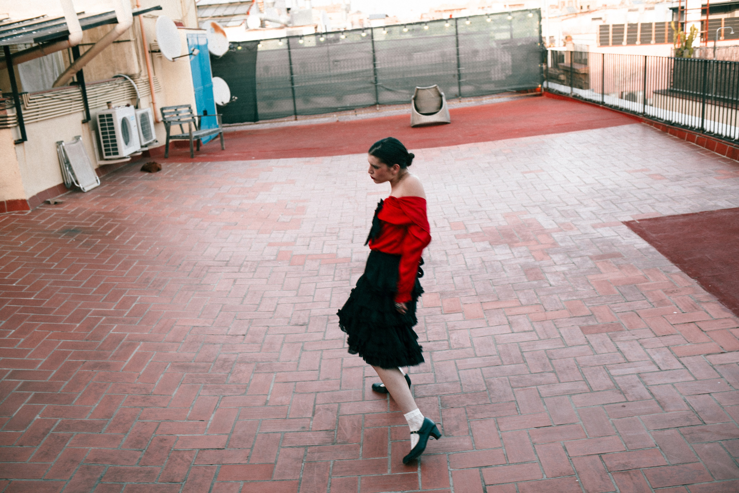Woman dancing on a rooftop in red and black outfit