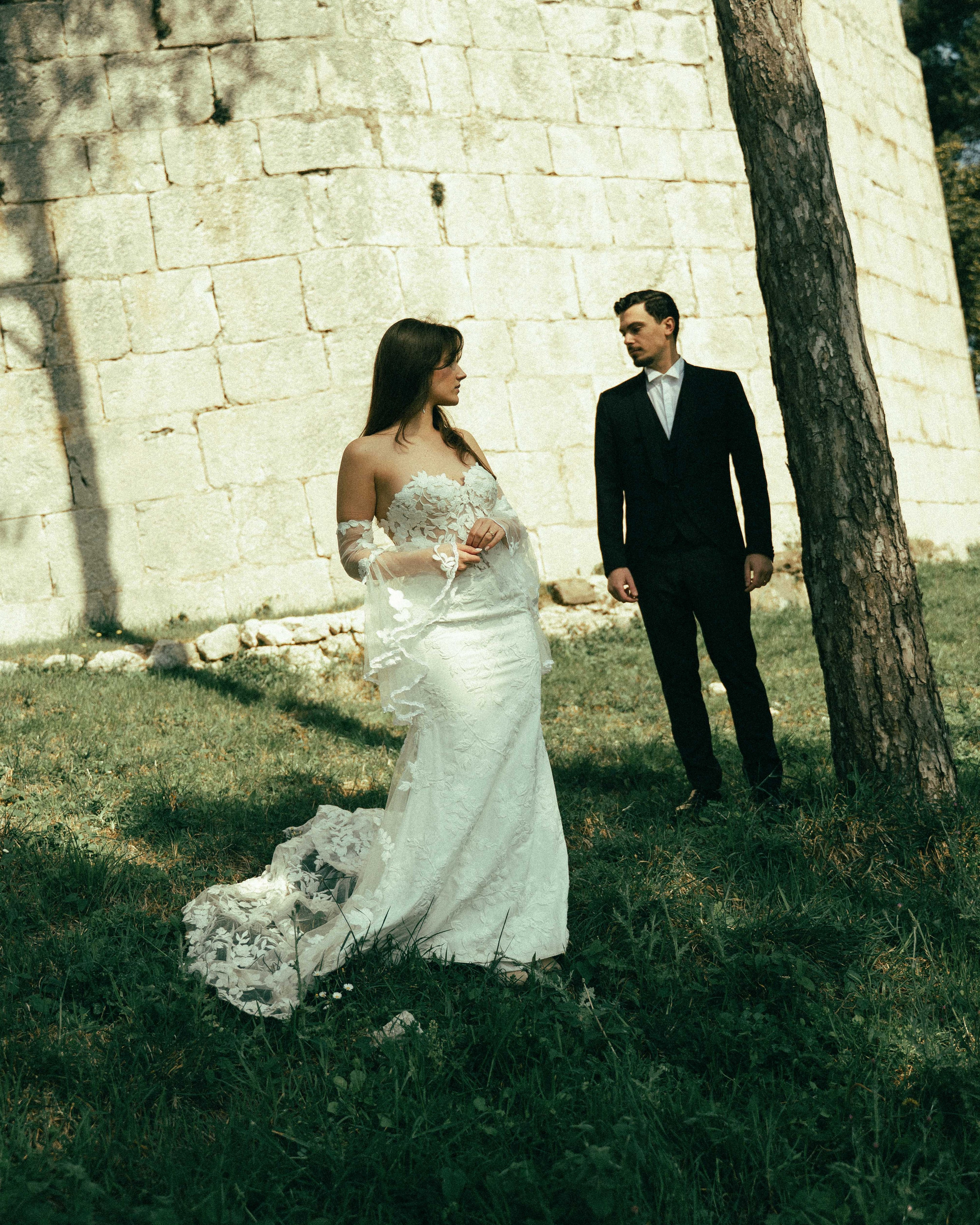 Elegant wedding portrait of bride and groom in a garden, looking in opposite directions