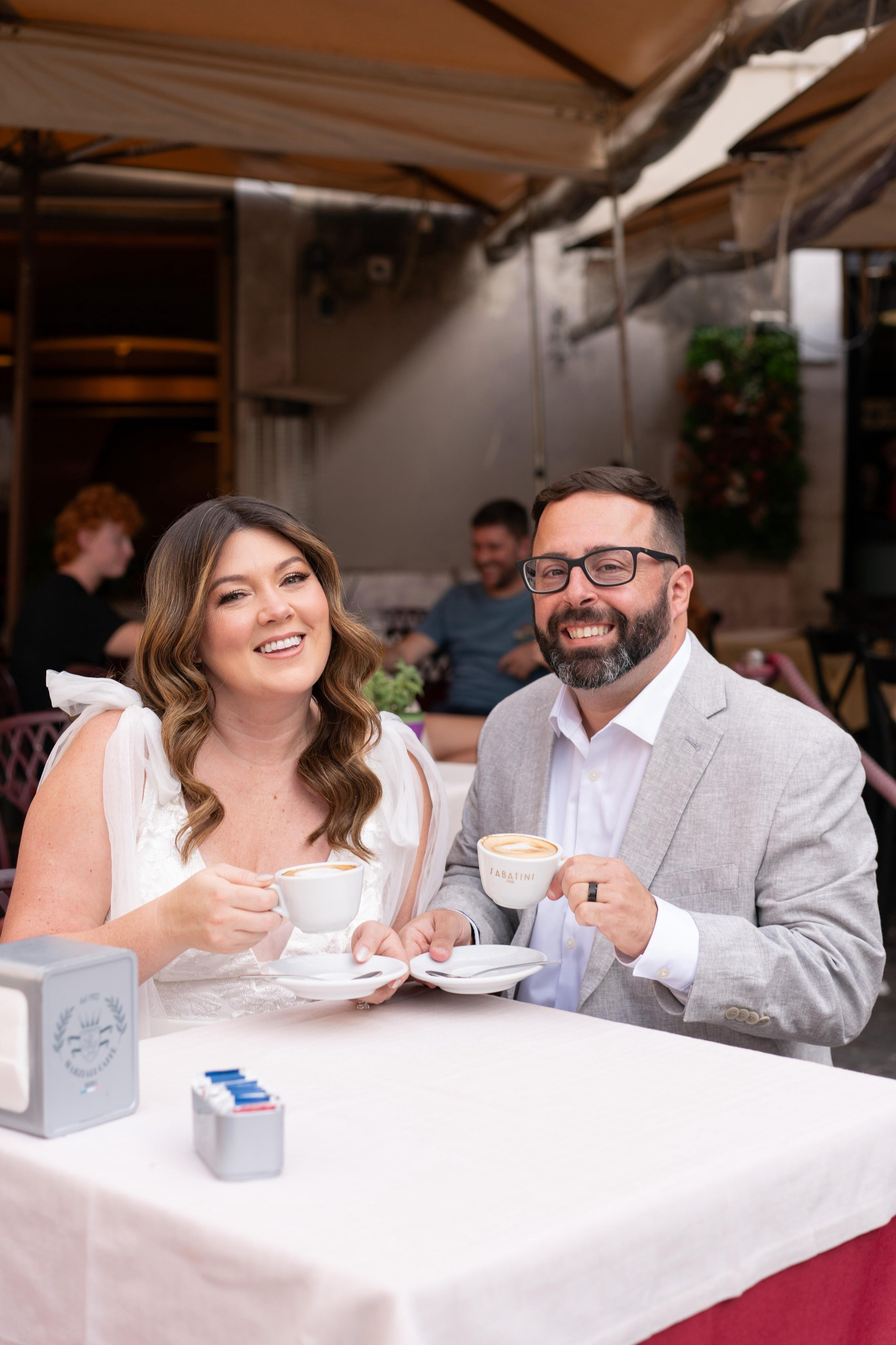 bride and groom sitting in a bar in piazza Navona drinking cappuccino