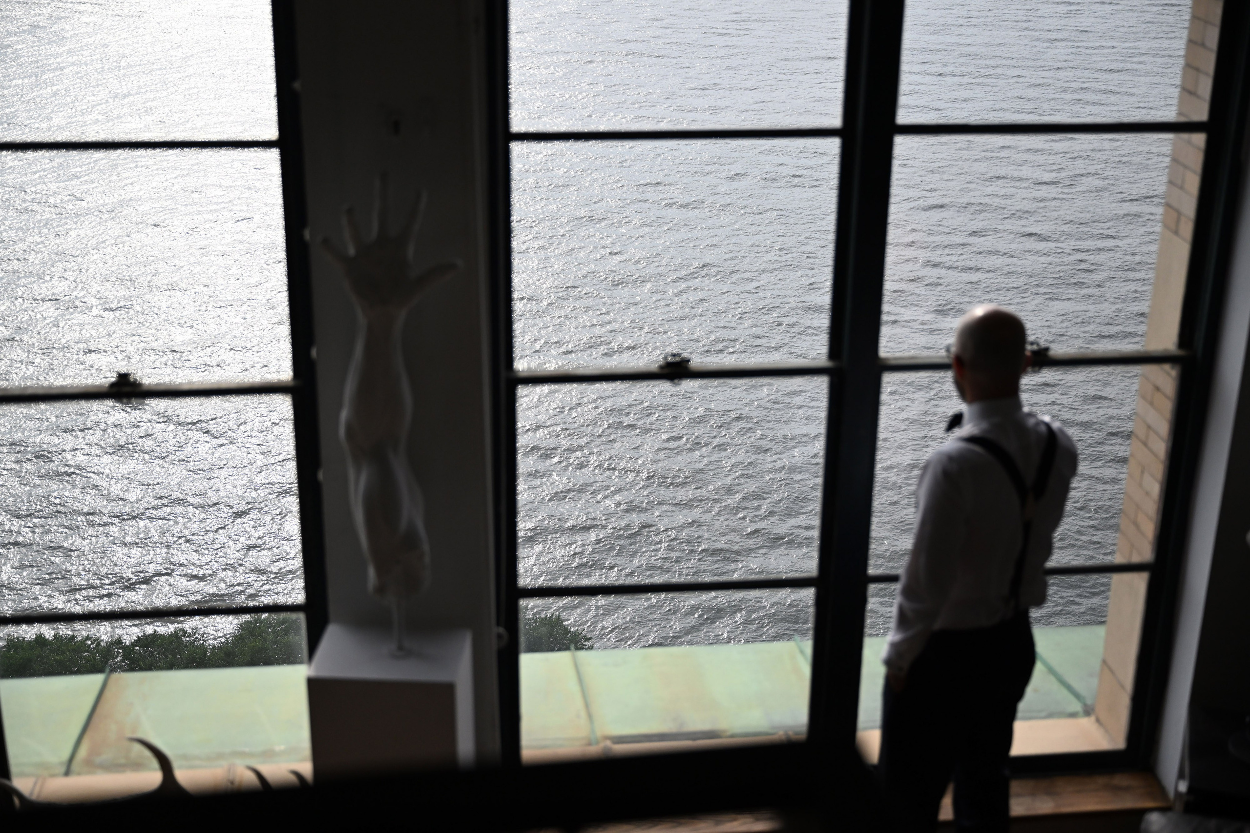 a man standing in front of a window looking out at the water