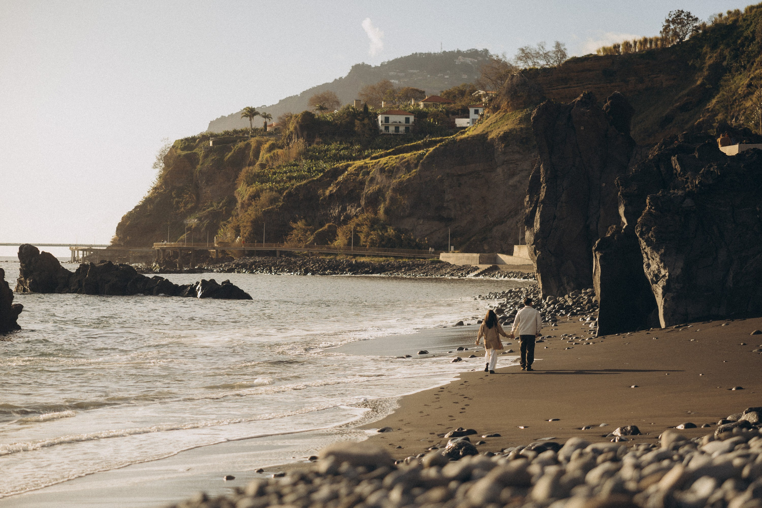 Couple sharing a romantic moment during sunset on Madeira Island, with the ocean and cliffs in the background