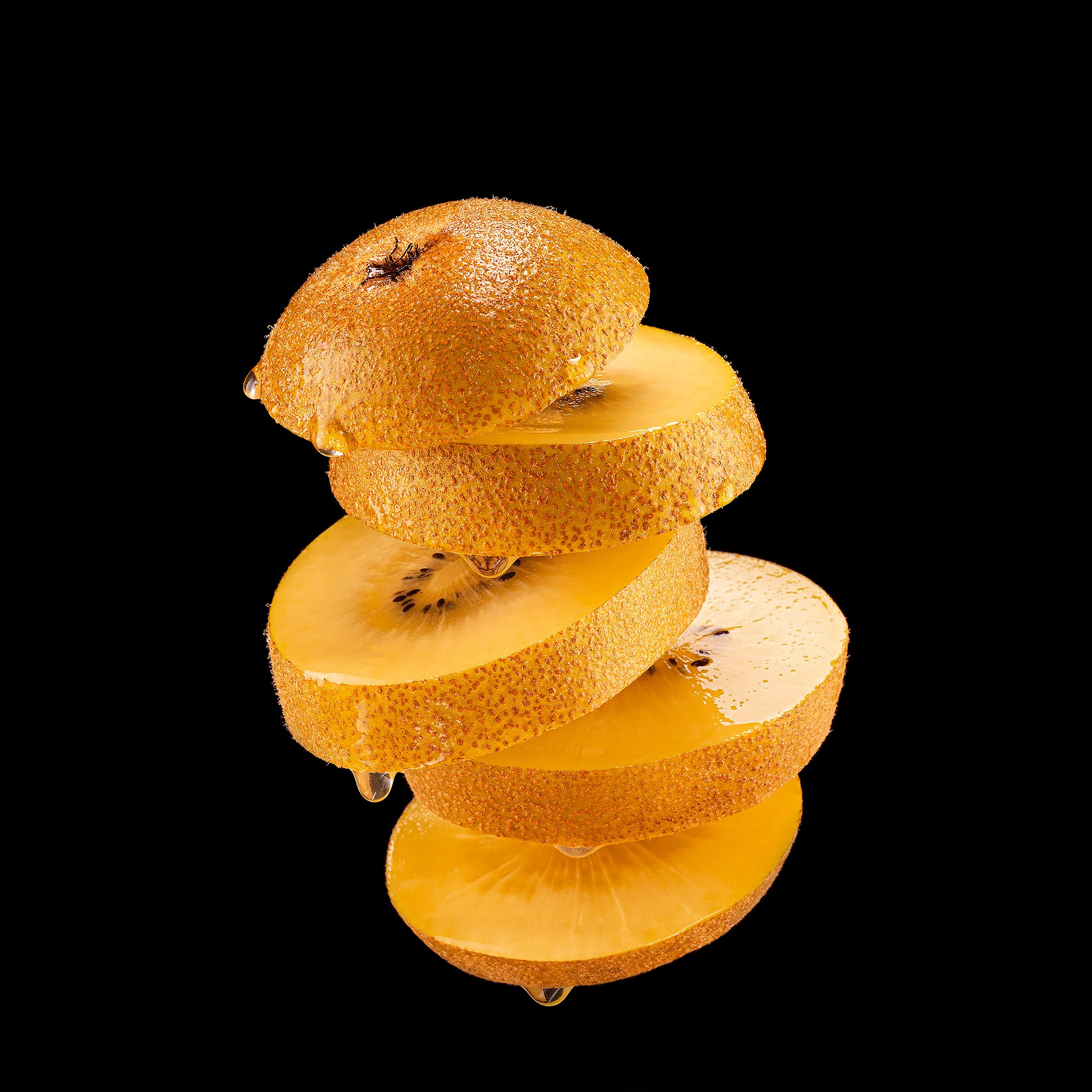 Photographer Roman Djuzev - Levitation of cut gold kiwi on a black background.