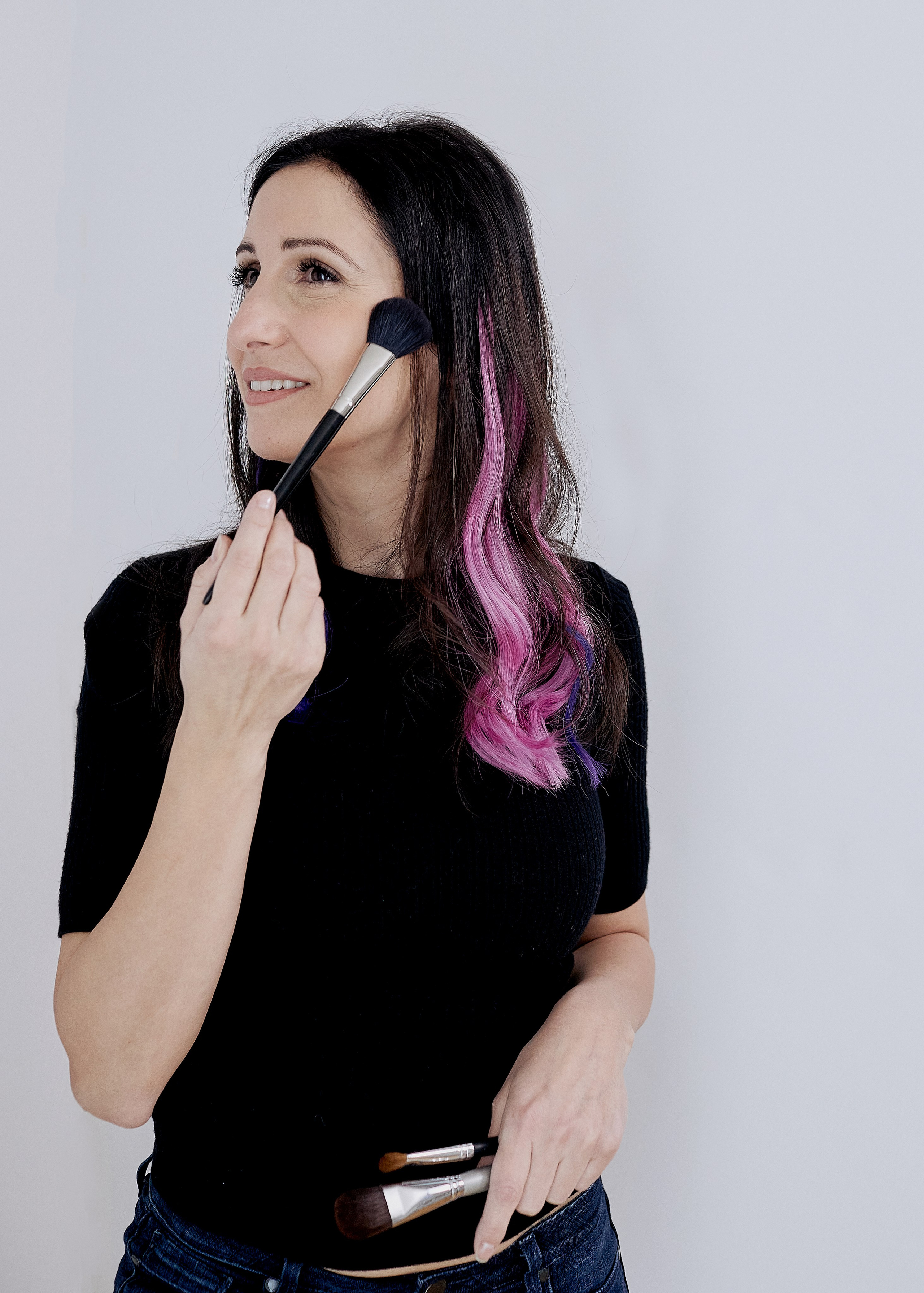 makeup artist sitting in chair holding her makeup tools 