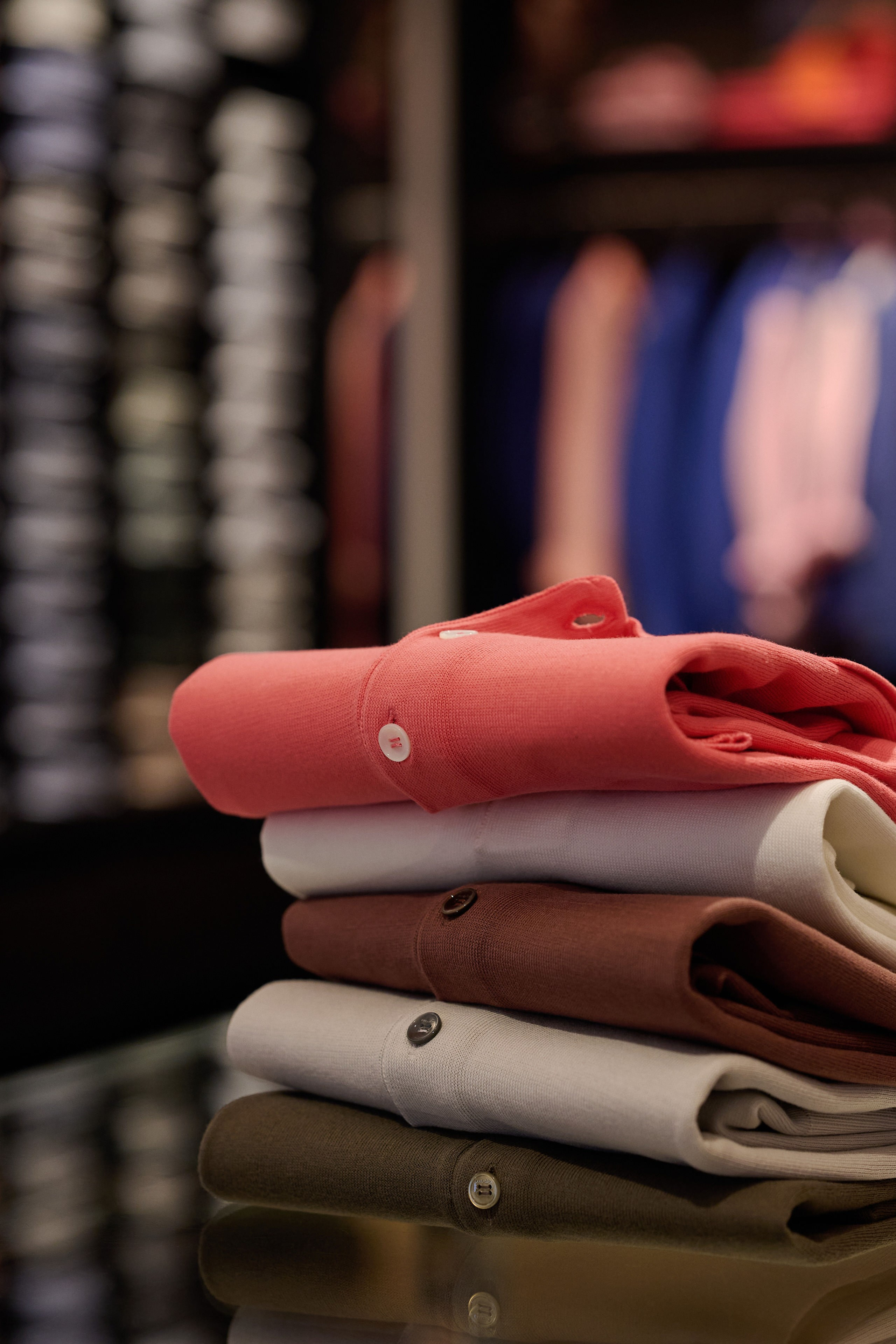 Produktfotografie Wien – Roter Wollpullover auf Maßtisch, im Hintergrund ein Modegeschäft mit Kleidung.