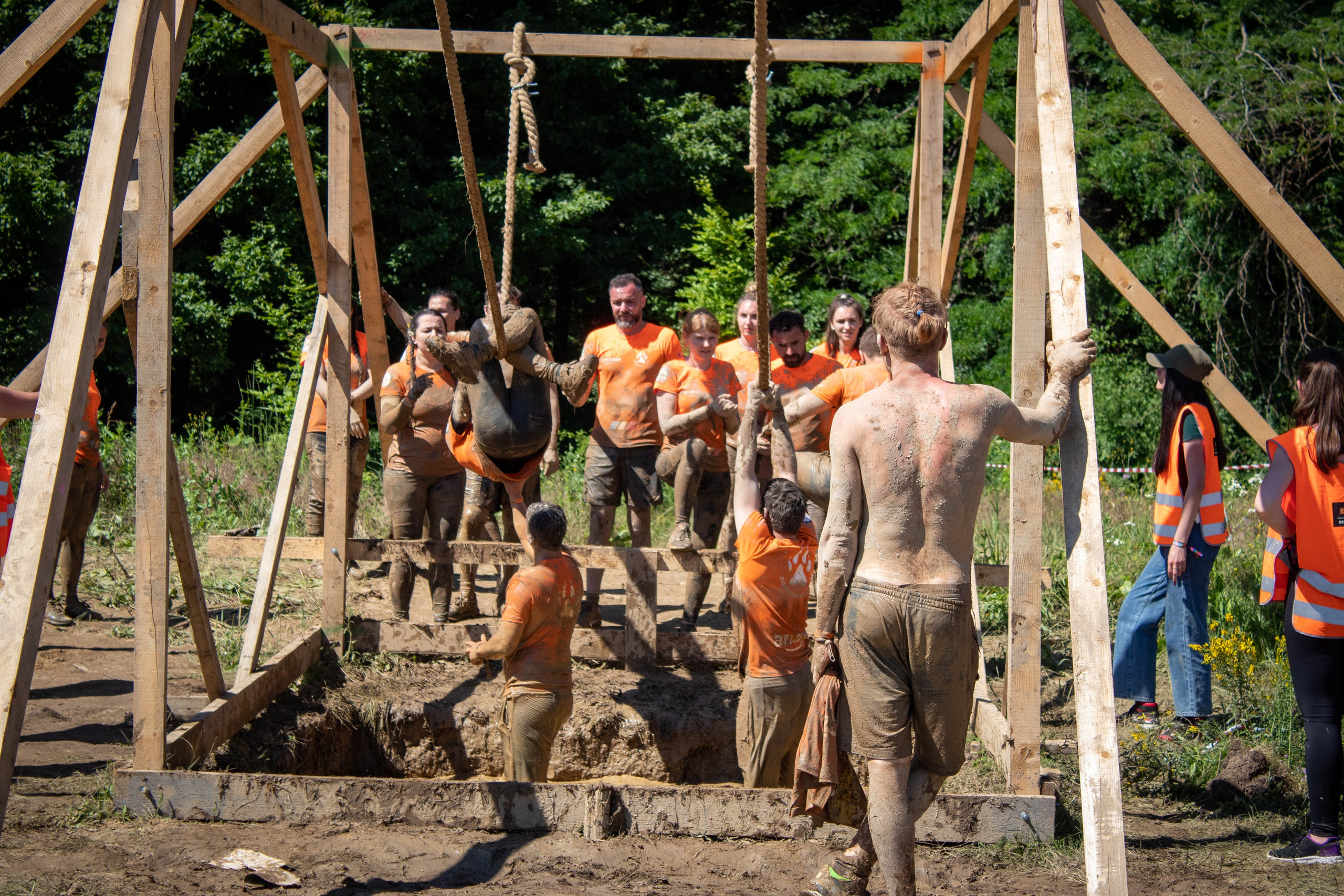 Group of competitors lifting a large wooden log as part of an outdoor obstacle course.