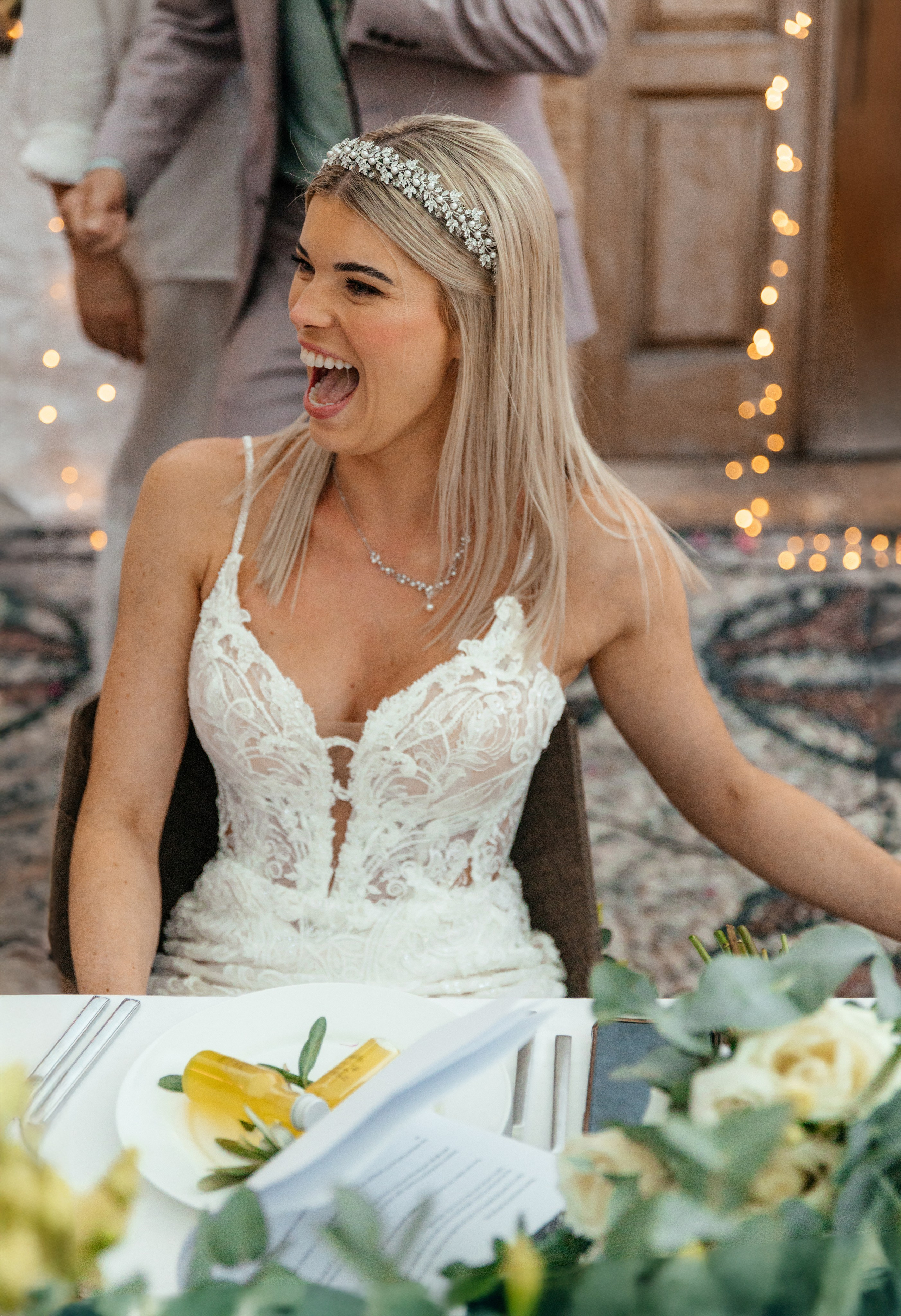 Bride is laughing during a humorous wedding speech by her brother at a charming restaurant in Lindos, Greece, Rhodes.