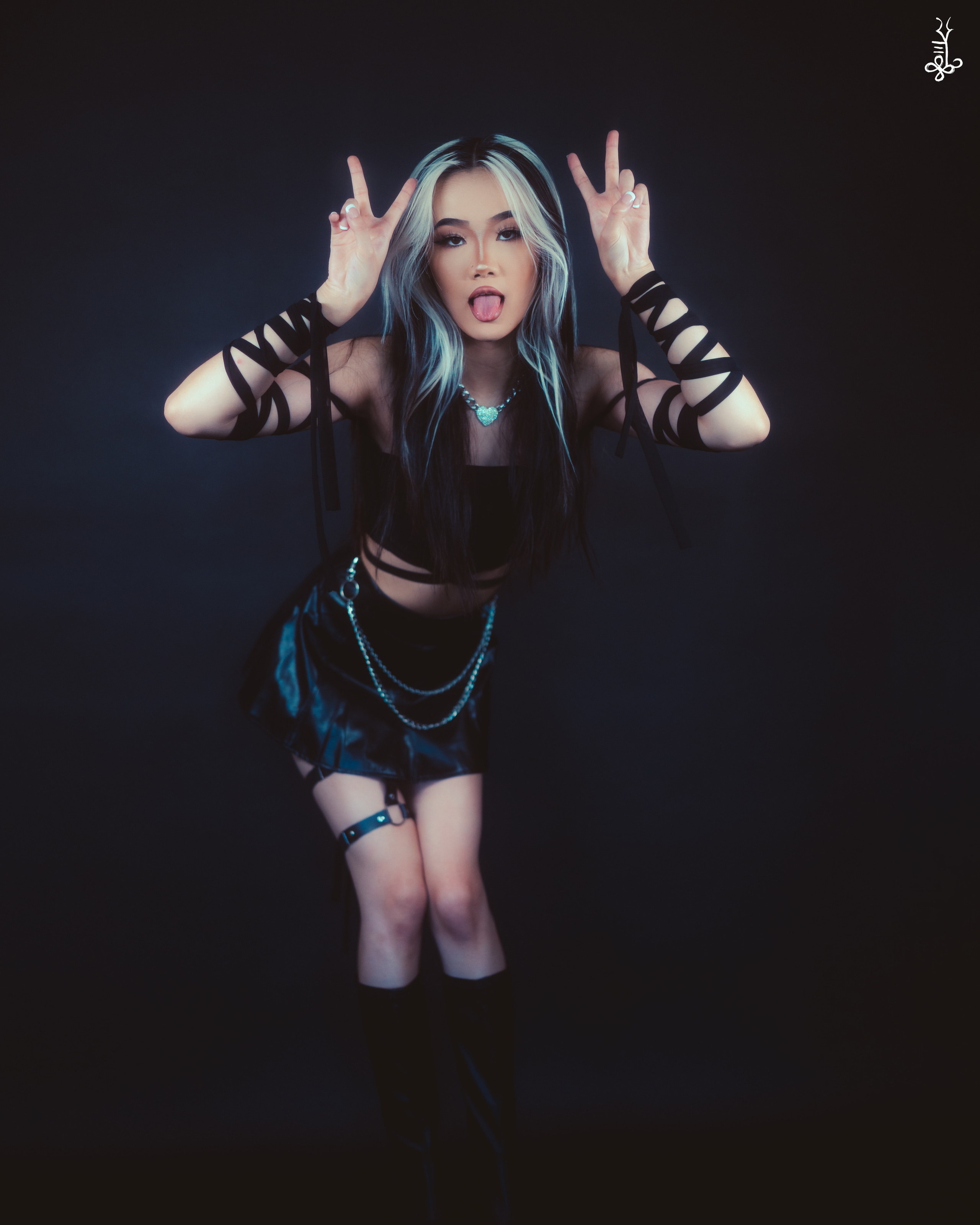 Model in fishnet and leather outfit under spotlight with black backdrop