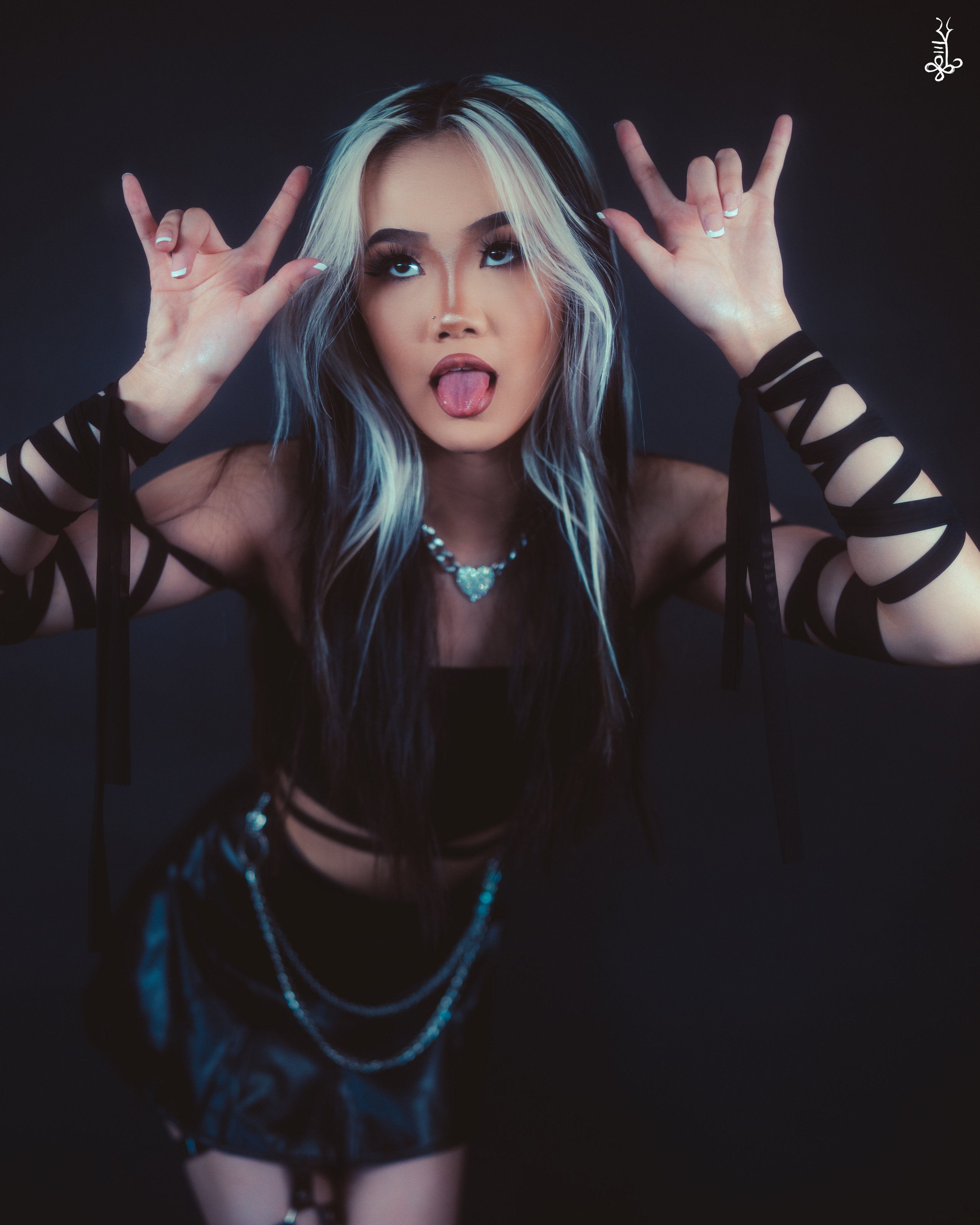Model with teal hair wearing a black mesh hoodie posing against a dark background