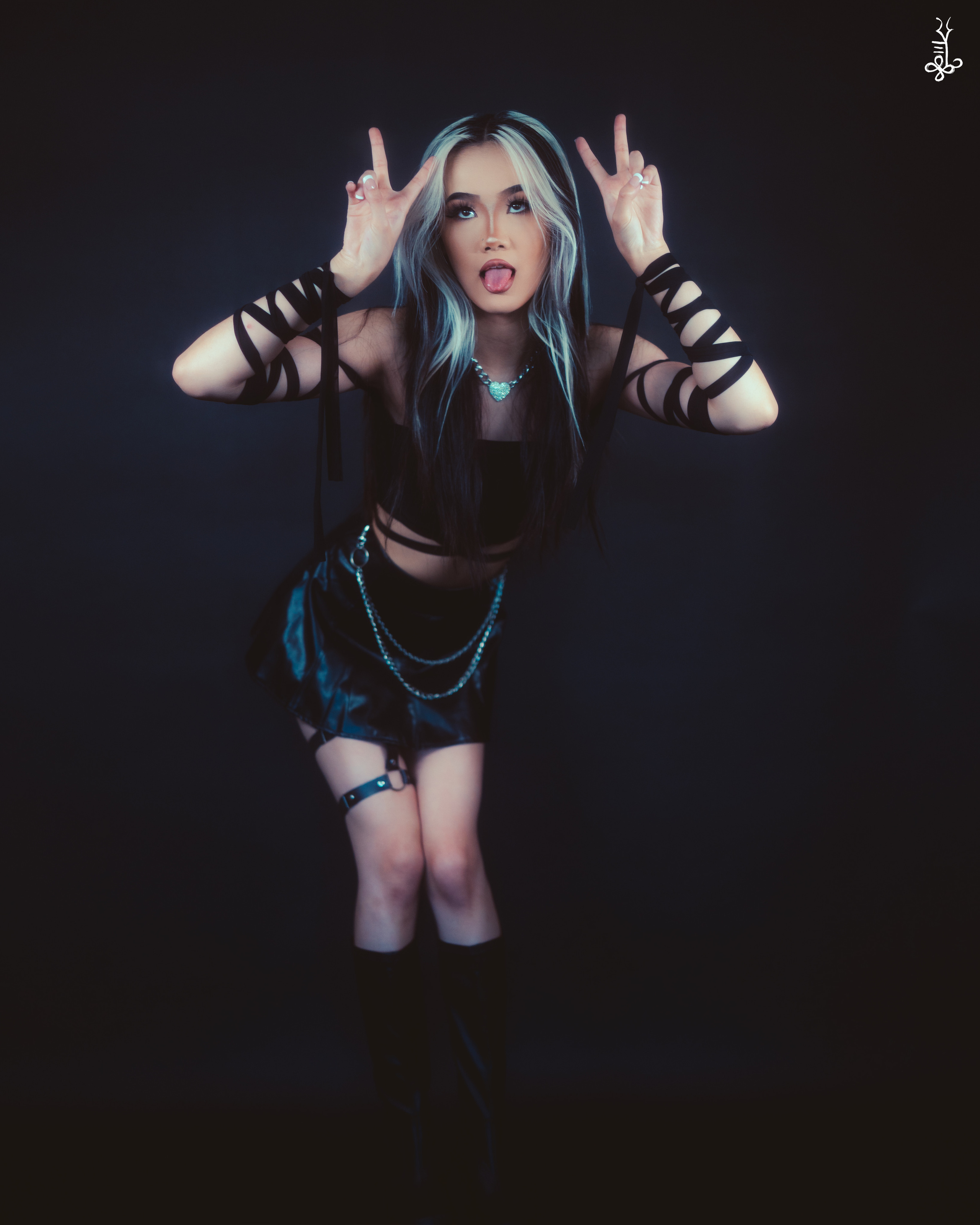 Full-body shot of model in edgy streetwear with arms raised in a dramatic pose