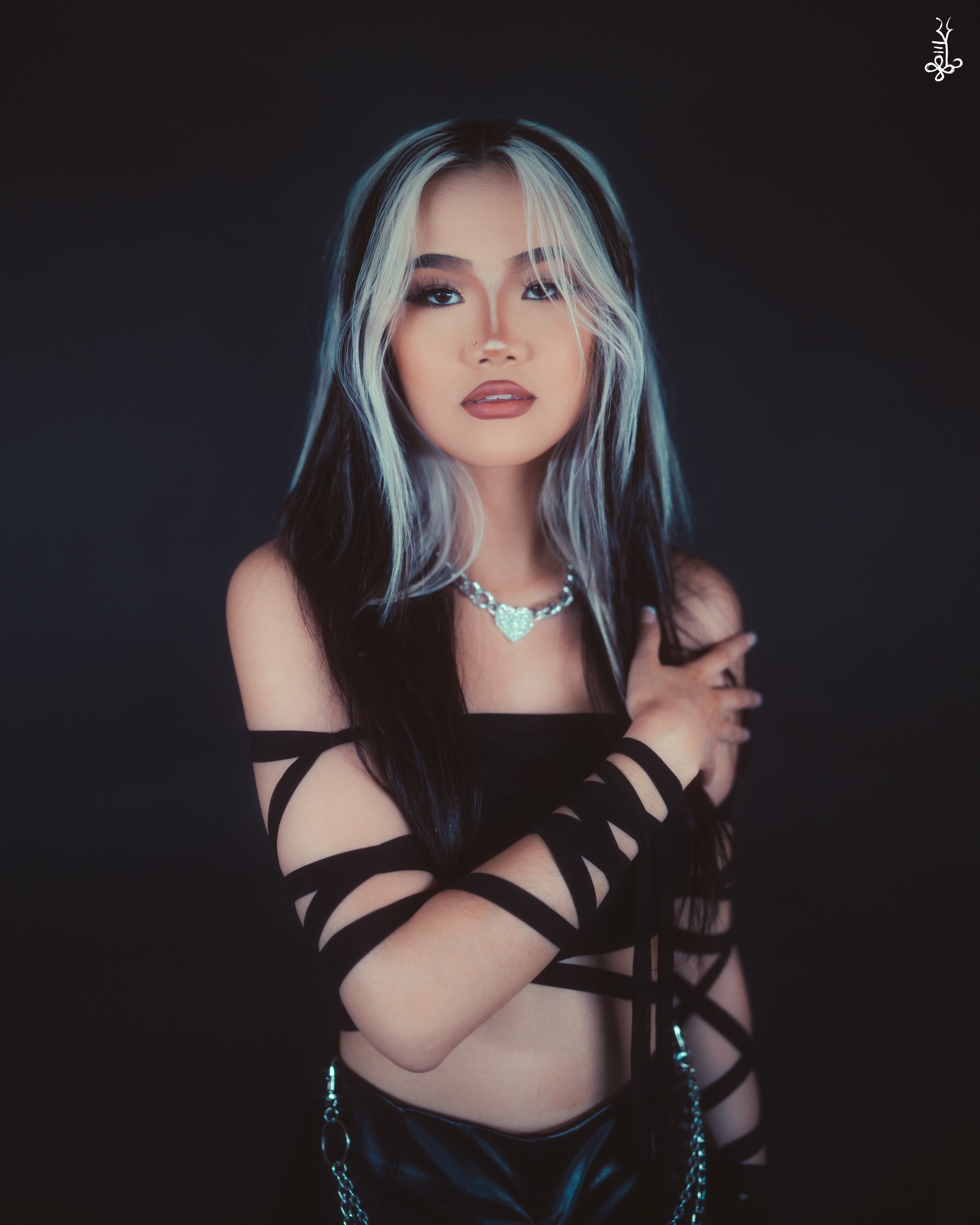 Model with turquoise hair in black cutout outfit staring fiercely ahead against black background