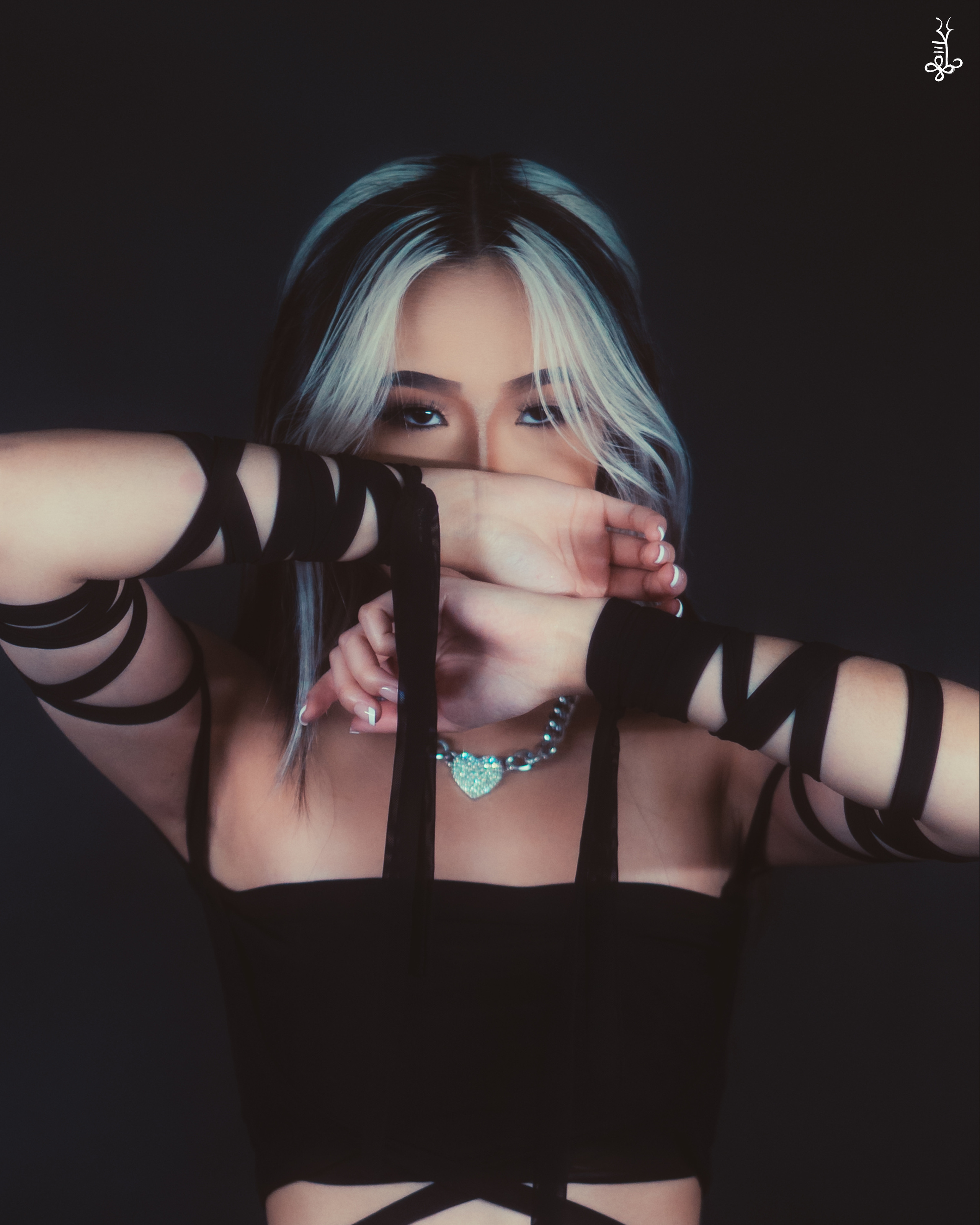 Model covering eyes with fingers, peeking through in dramatic lighting and dark attire